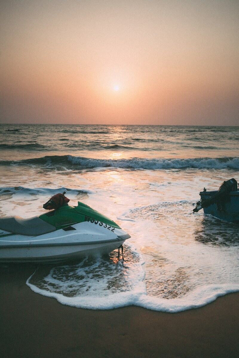 Watercraft rest in the Goa surf at sunset. print option