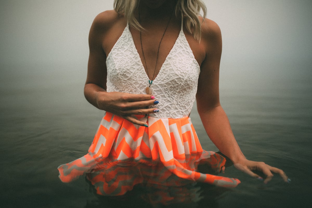 A seated figure in white and orange at Okanagan Lake in Kelowna, with forest-fire smoke turning the lake air pale and stark. print option