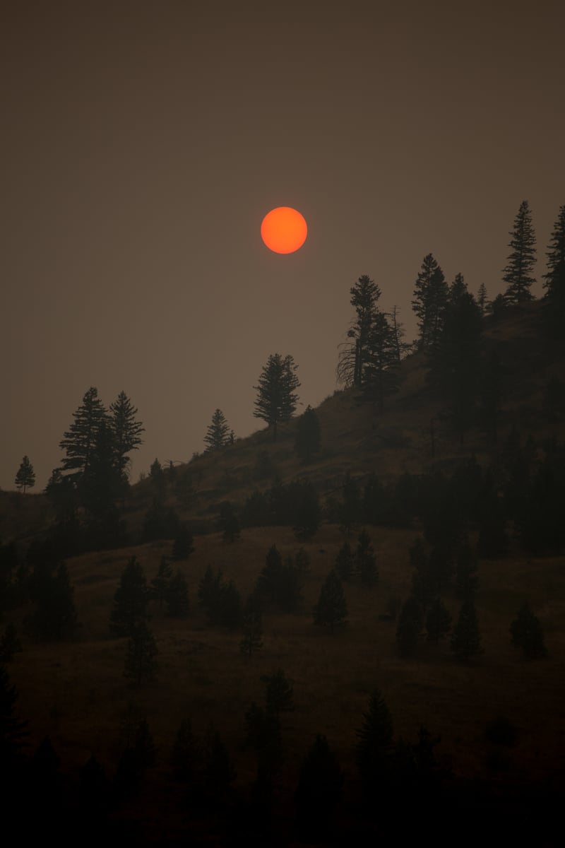 A forest-fire-red sun burns through smoke over the ridge country toward Pemberton, photographed after a Whistler yoga retreat. print option