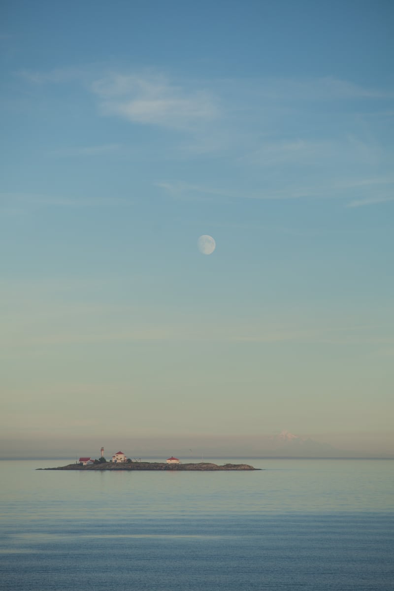 A small boat crosses a pale blue horizon off Vancouver Island. print option