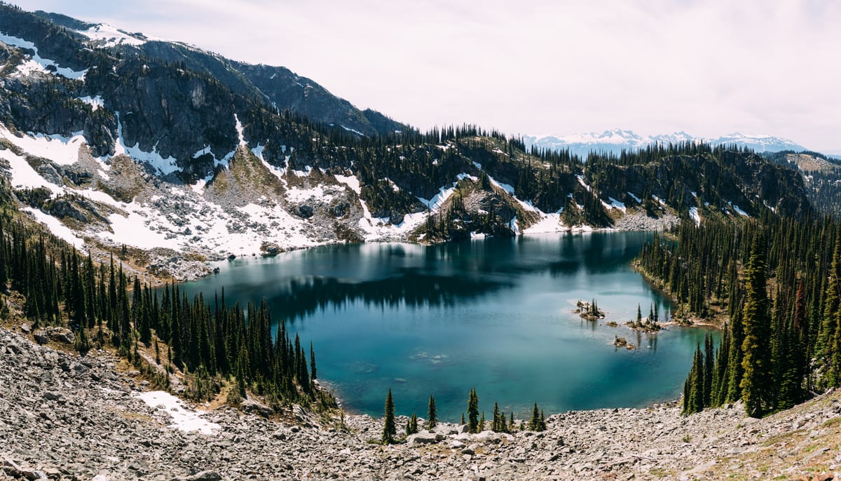 A wide Mount Revelstoke alpine lake held by rock, snow and summer sky. print option