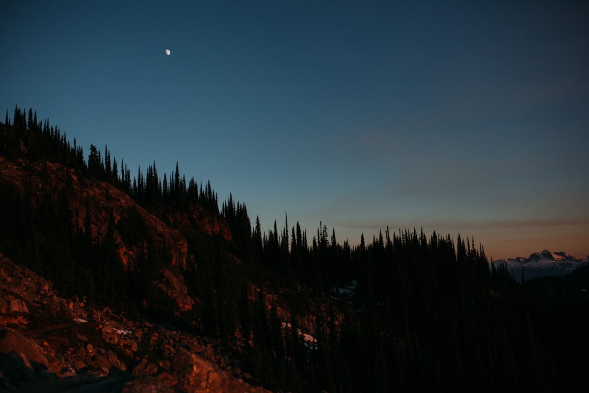 The moon rises above a dark Mount Revelstoke ridge at blue hour. print option