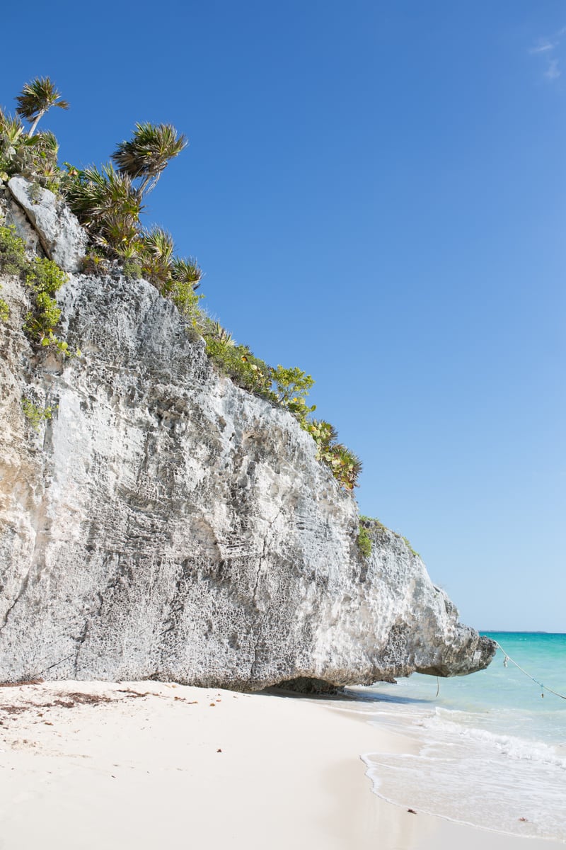White Tulum limestone, blue water and cliff plants under clear sky. print option