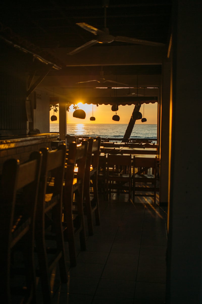 A warm interior frame looking toward a Costa Rica sunset beyond the rail. print option