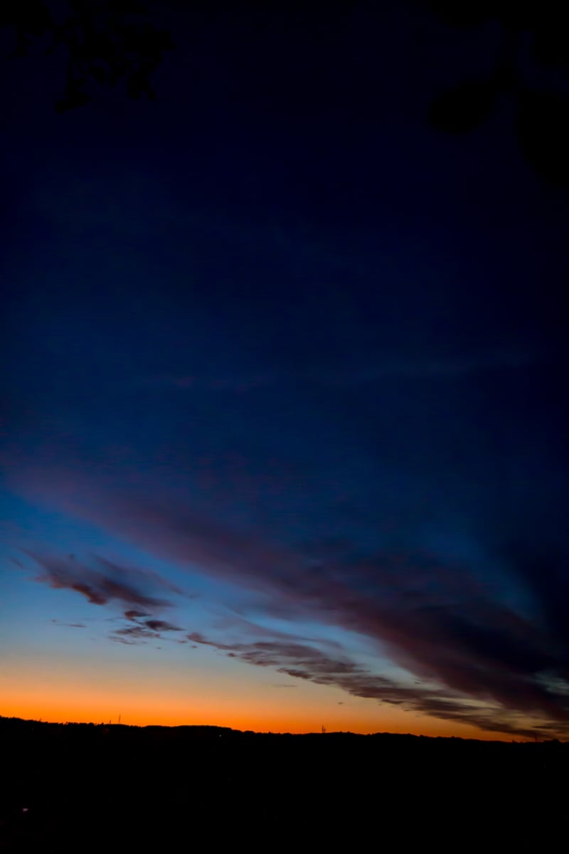 A blue-hour cloud shape sits above a thin orange Peterborough horizon. print option