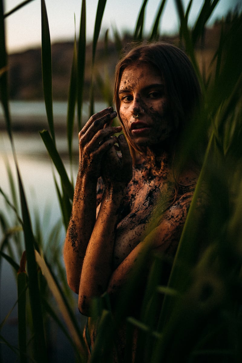 Mo in the Reeds story frame 19: Green shadow, tall grass, body paint and a charged quiet that stays grounded in portrait atmosphere.