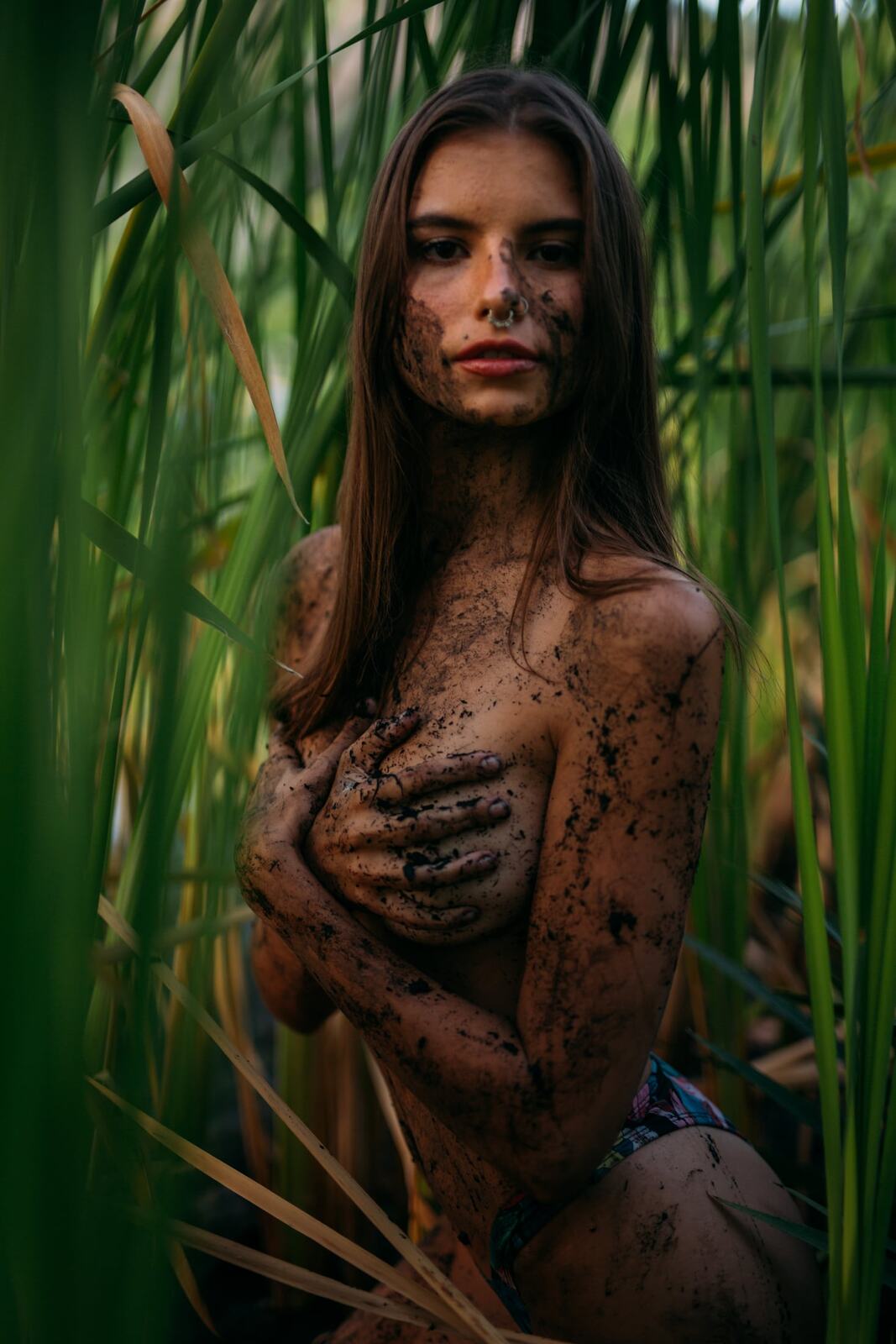 Mo in the Reeds story frame 13: Green shadow, tall grass, body paint and a charged quiet that stays grounded in portrait atmosphere.