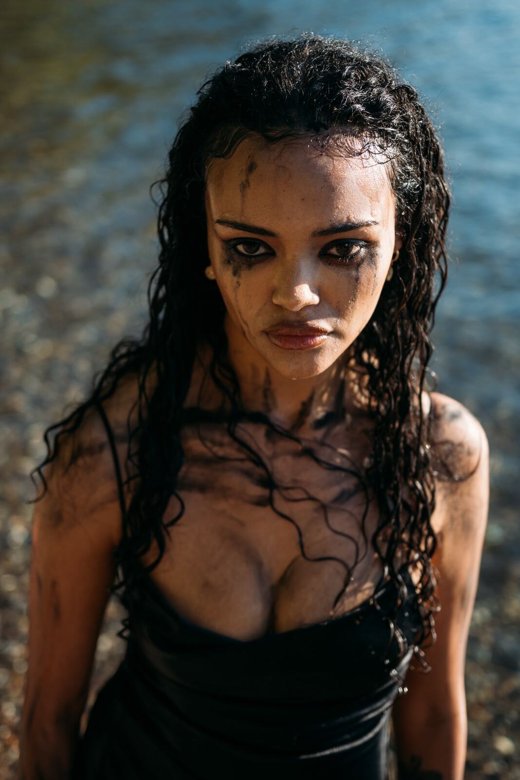 Alex by the Lake portraits story frame 10: Okanagan Lake portraits in Kelowna with black styling, rock, water, wind, direct expression and a cinematic beauty-portrait edge.