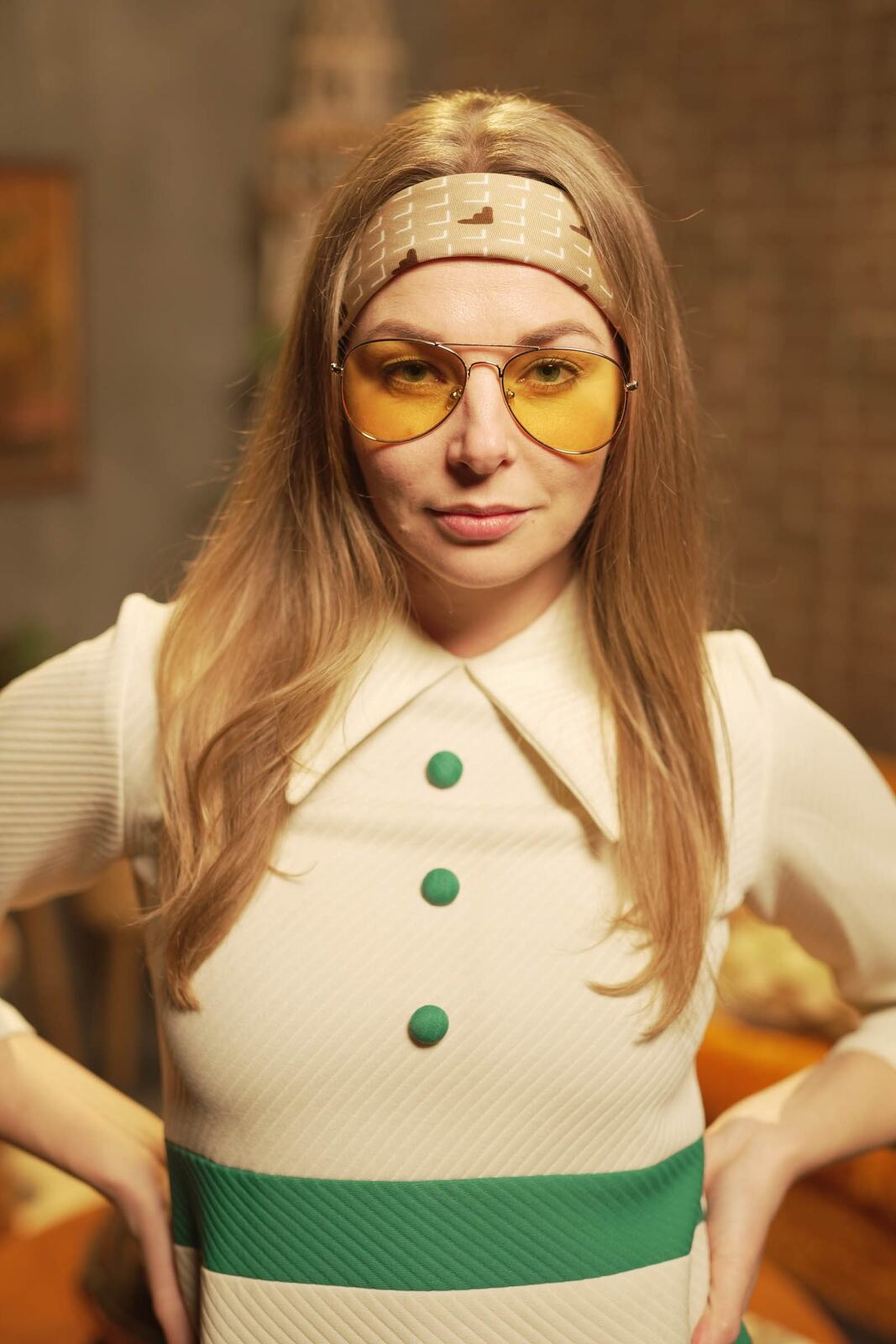 Angela in the 70s Lounge portraits story frame 1: A warm 70s lounge portrait story with yellow glasses, retro styling, couch texture and a softer studio mood.