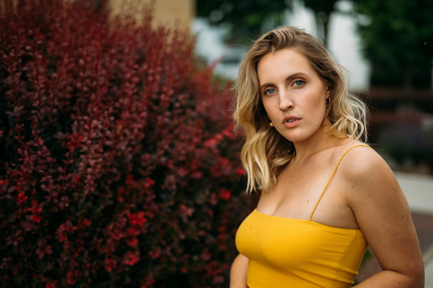 Brittany in Yellow and Blue portraits story frame 6: A two-look Kelowna portrait story for Brittany, led by the yellow styling and dark green texture, then moving into blue lakeside frames and a soft rainbow-bokeh finish.