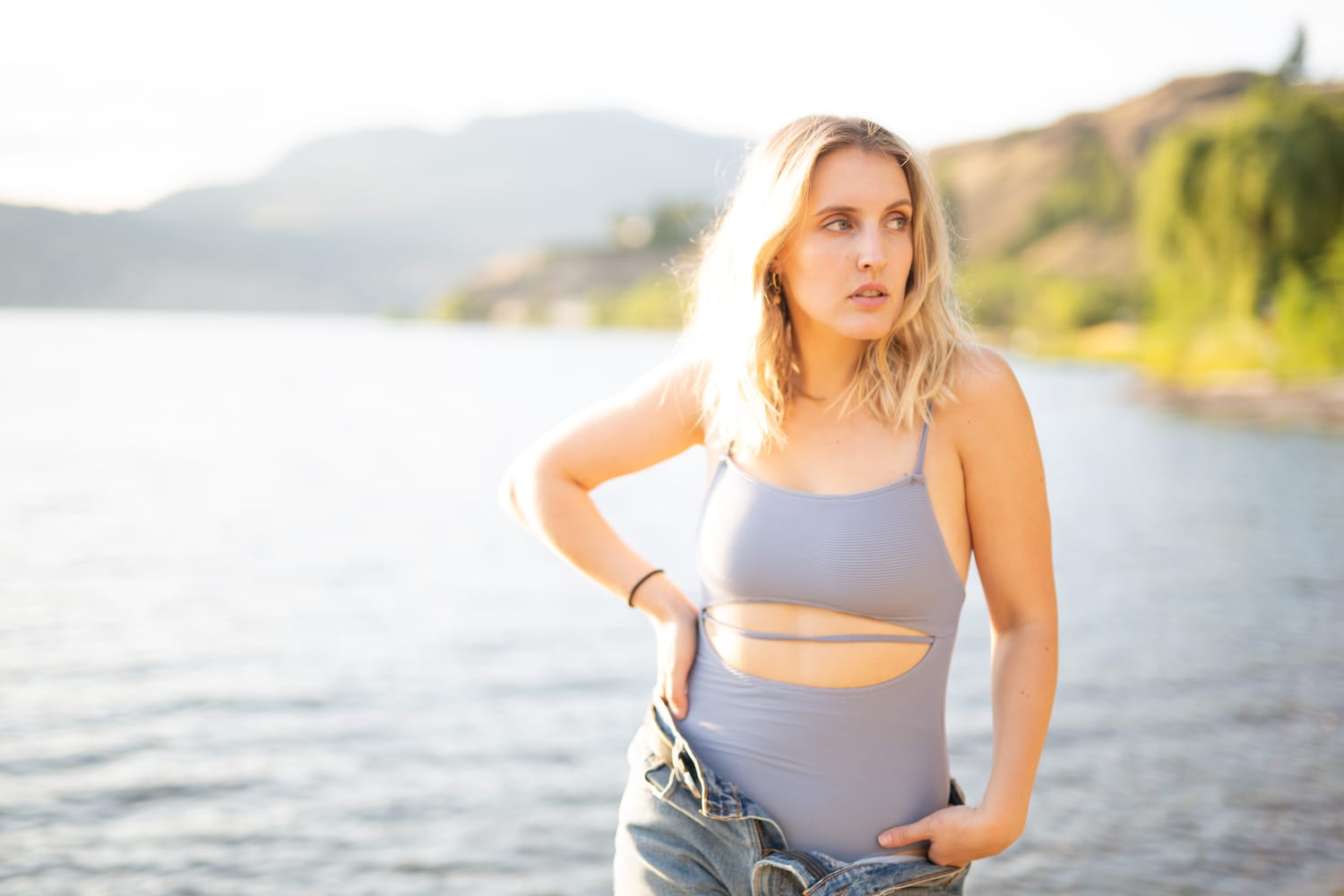 Brittany in Yellow and Blue portraits story frame 17: A two-look Kelowna portrait story for Brittany, led by the yellow styling and dark green texture, then moving into blue lakeside frames and a soft rainbow-bokeh finish.