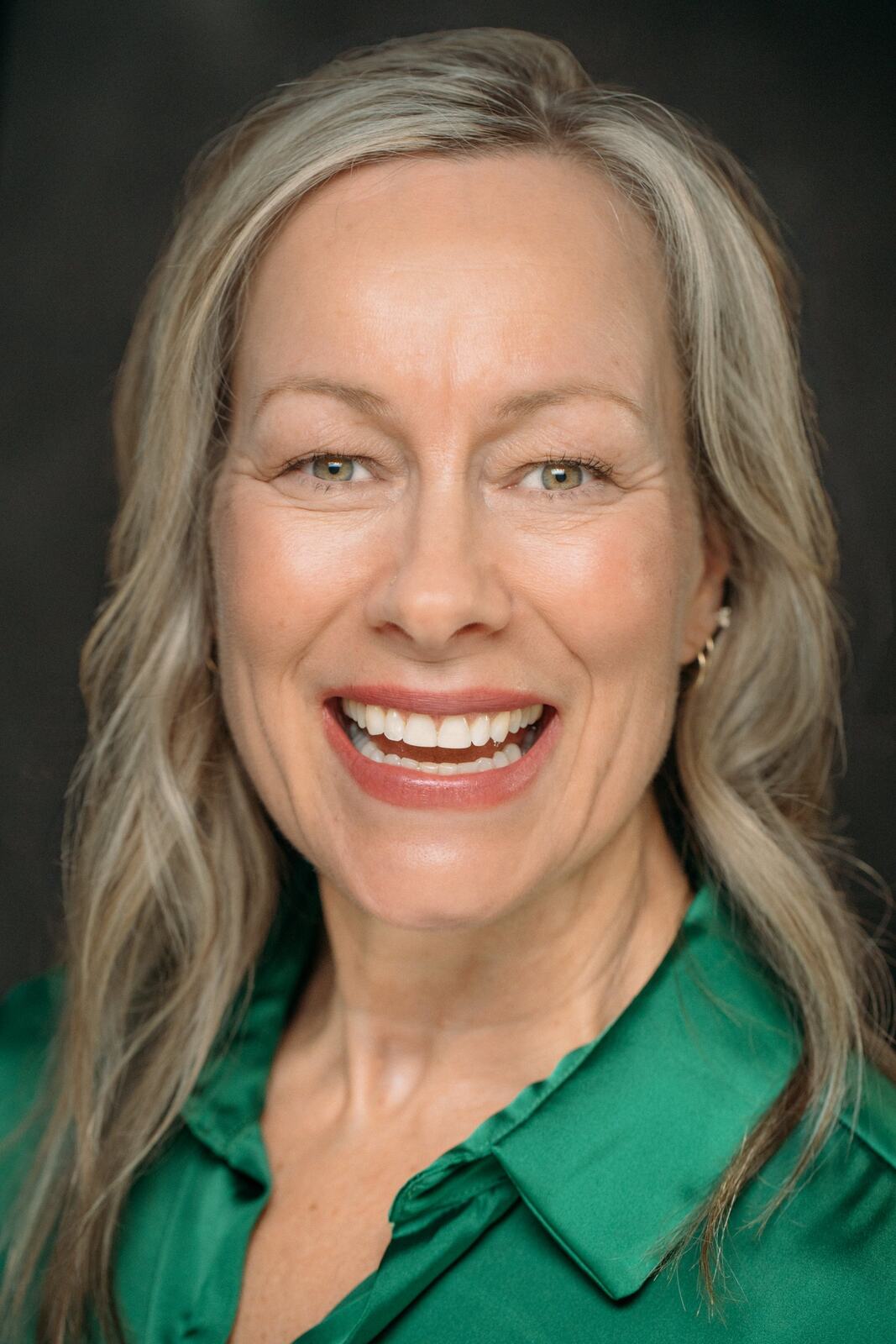 Shaye smiling in a bright green Headshot Day portrait