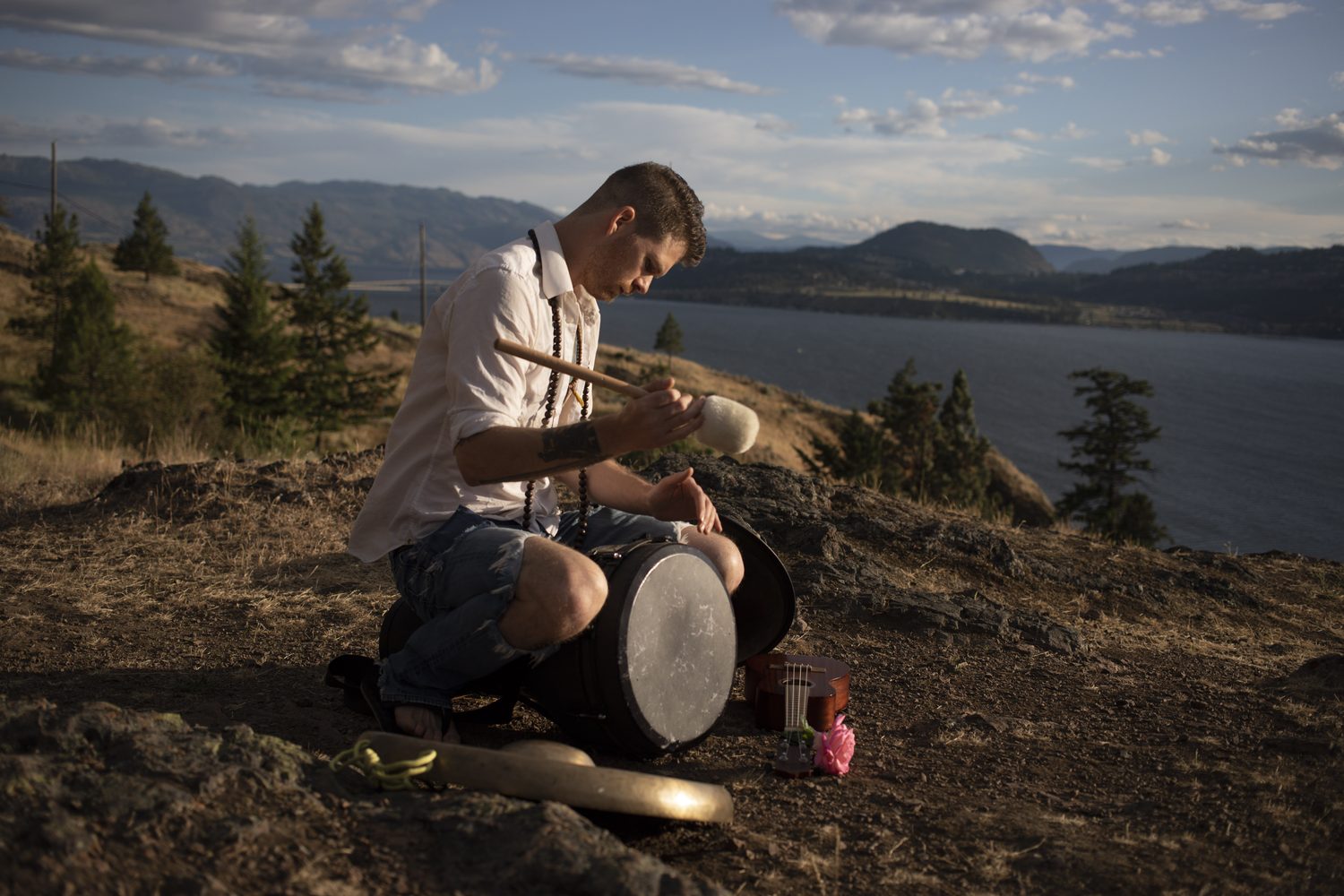 Jacob playing handpan on the hillside above the lake.