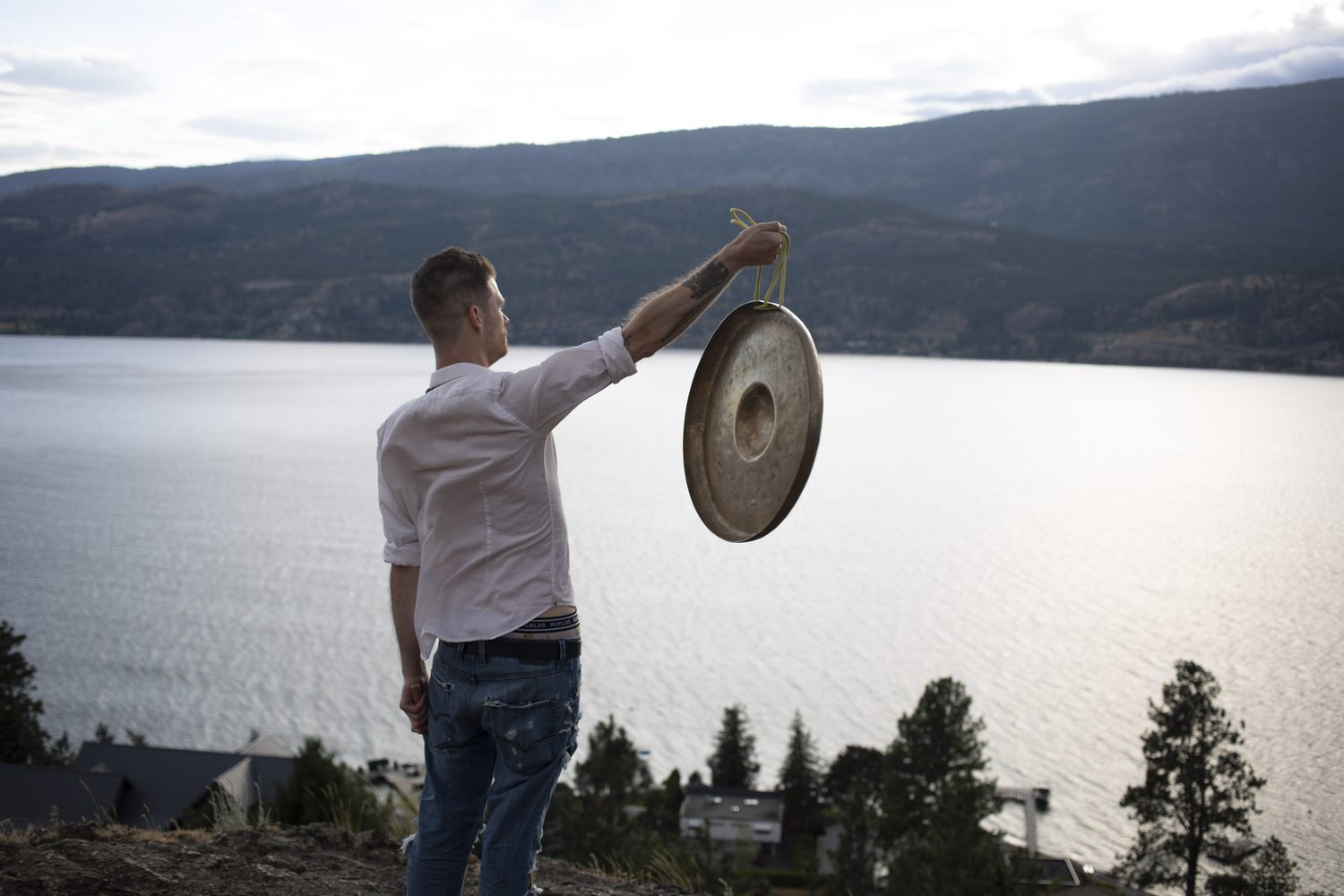 Jacob lifting a gong with the lake stretching behind him.