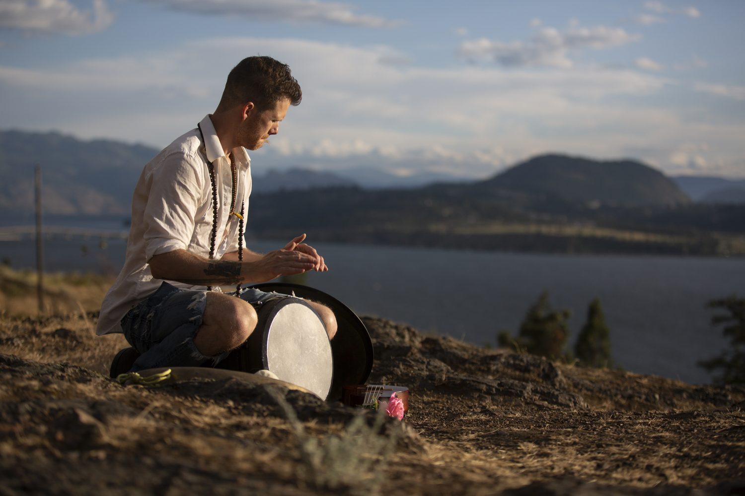 Jacob playing handpan in warm evening light above the lake.