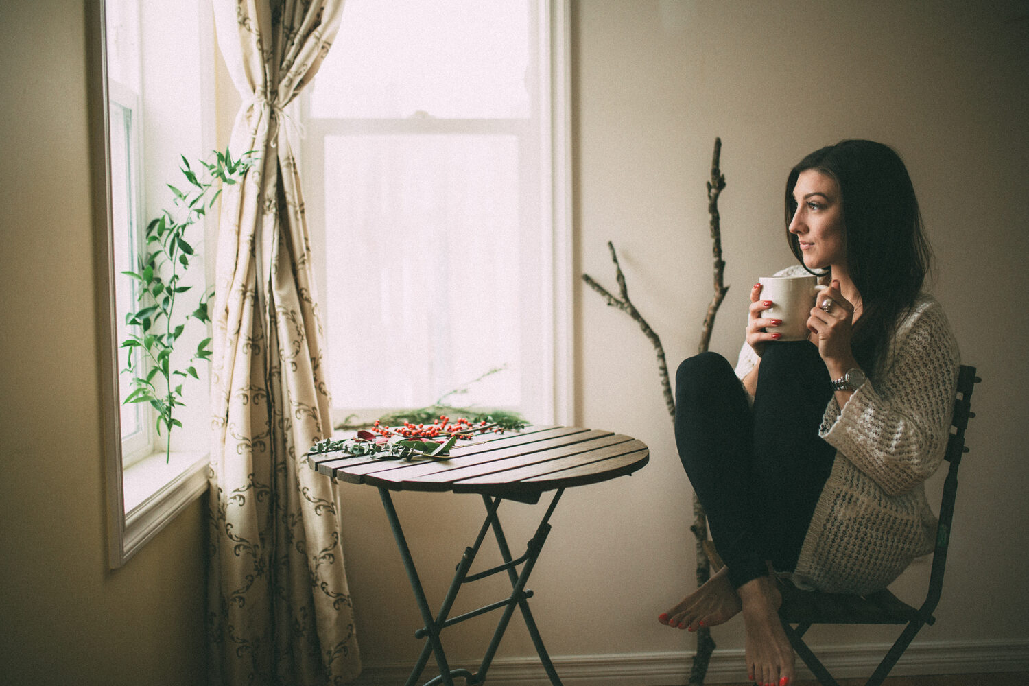 Jasmin by the Window portrait story frame 5: Window-light portraits with Jasmin beside a small table, tea and winter greenery in Kelowna, British Columbia.