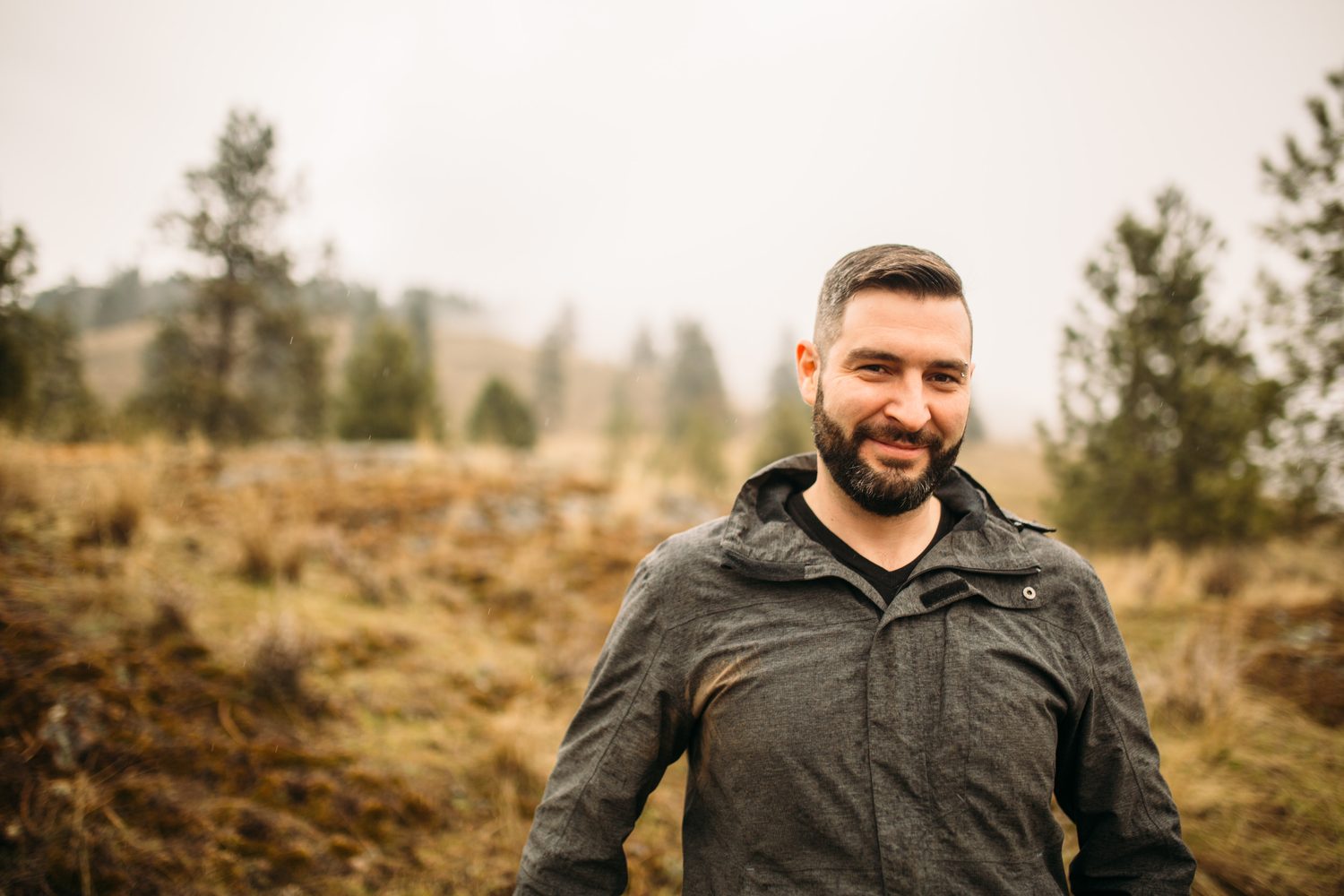 Jeremy standing in warm hillside light in a dark blazer for Optimize Organics.