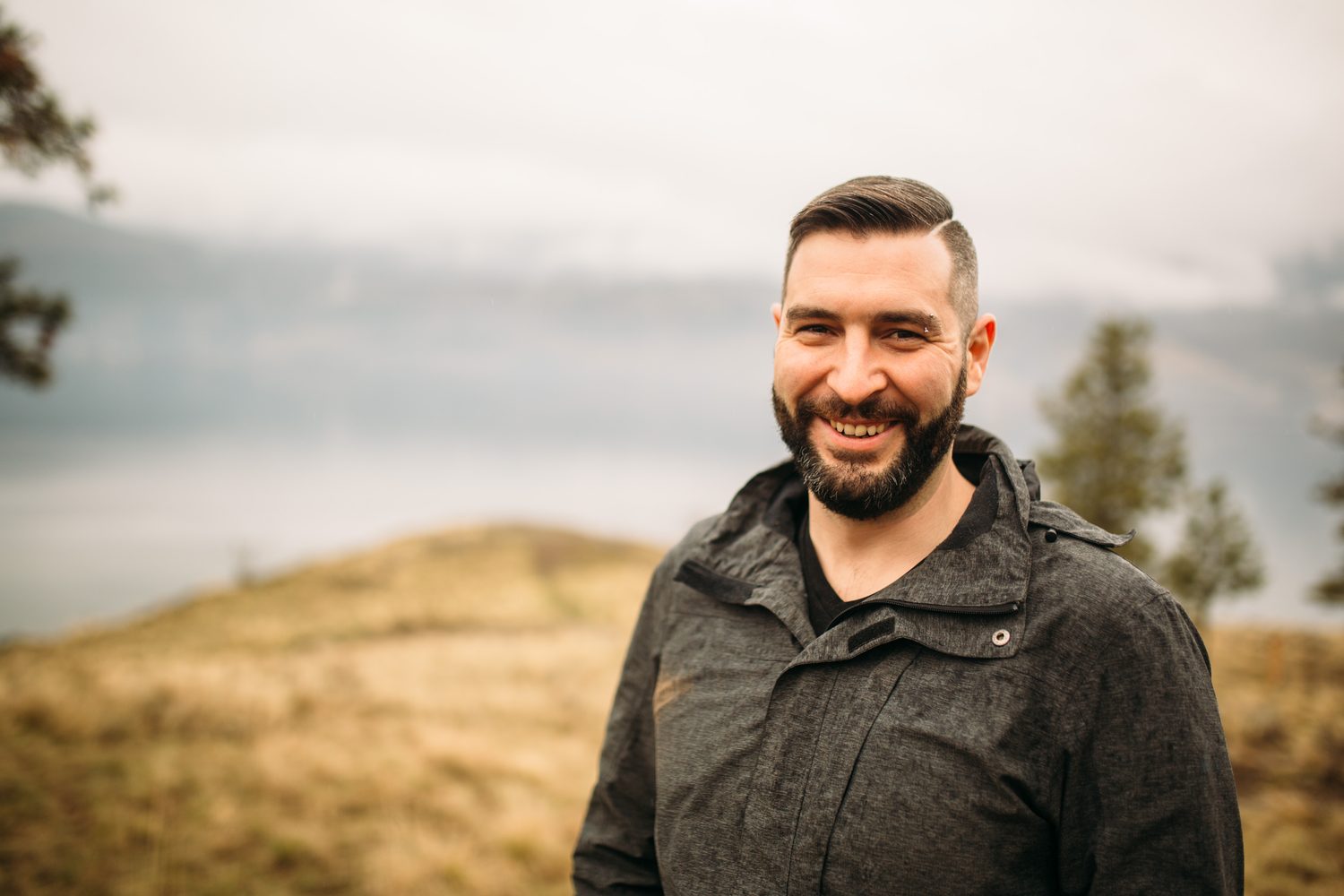 Jeremy standing in warm hillside light in a dark blazer for Optimize Organics.