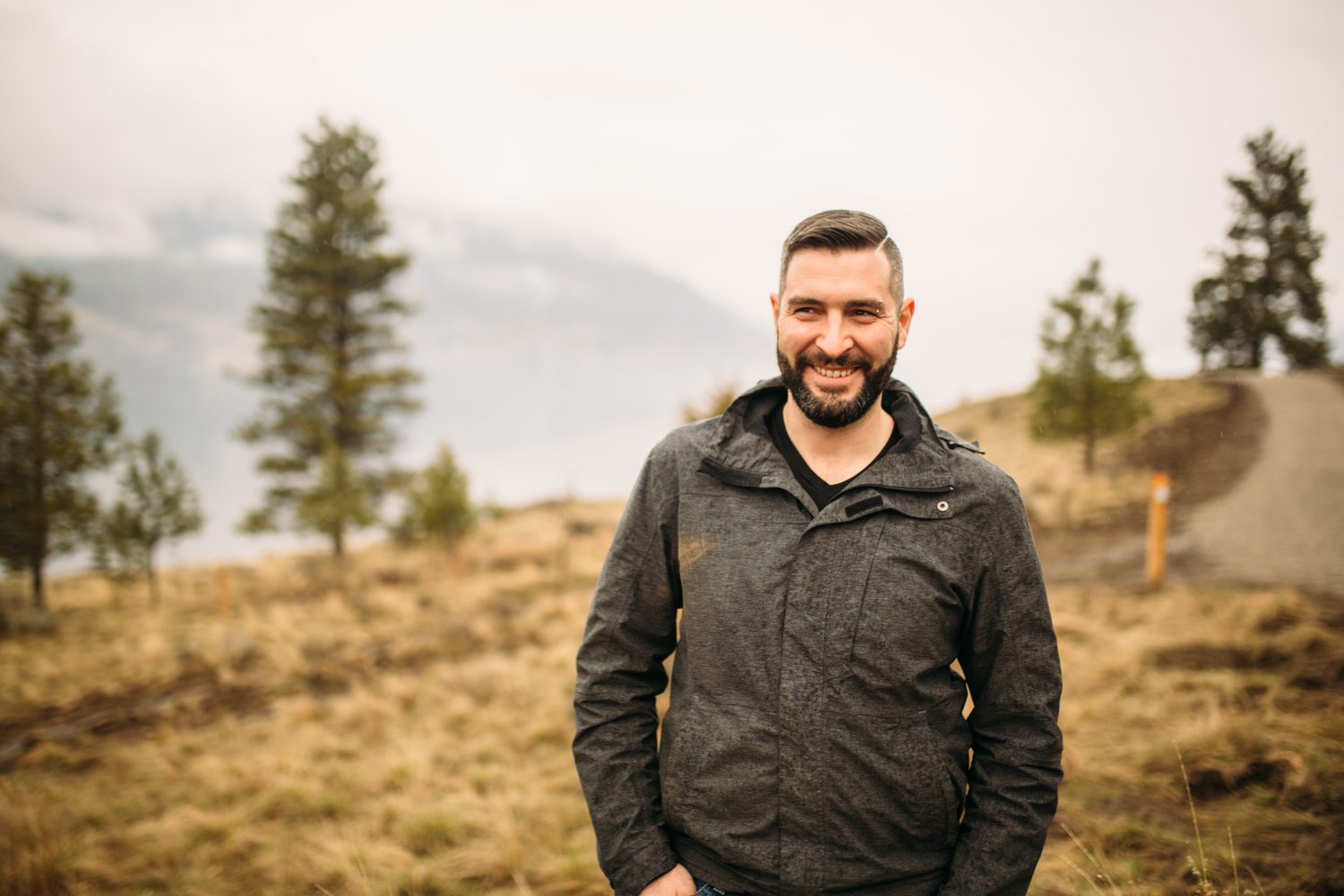 Jeremy standing in warm hillside light in a dark blazer for Optimize Organics.
