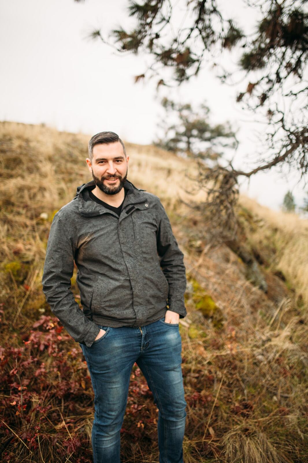 Jeremy standing in warm hillside light in a dark blazer for Optimize Organics.