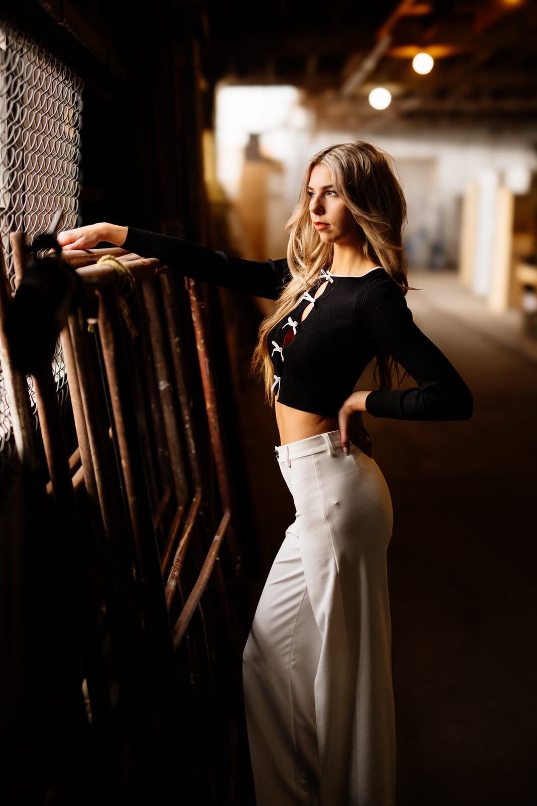 Kaylee in Clouds portraits story frame 10: Penticton portraits for Kaylee with cloud styling, warm industrial light, black lace-up wardrobe, white pants and an evening back-alley portrait sequence.