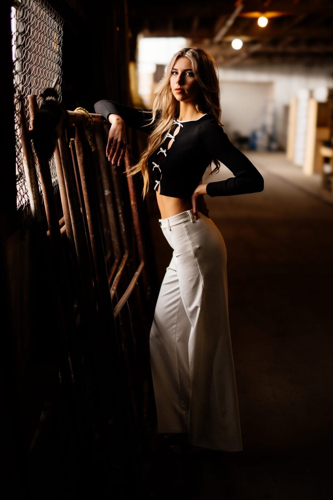 Kaylee in Clouds portraits story frame 11: Penticton portraits for Kaylee with cloud styling, warm industrial light, black lace-up wardrobe, white pants and an evening back-alley portrait sequence.
