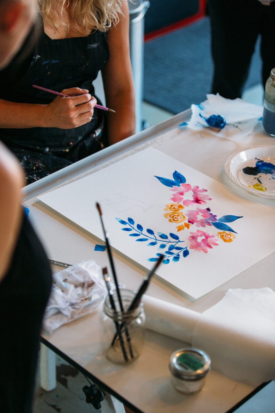 Participant painting a taped floral sheet at the table.