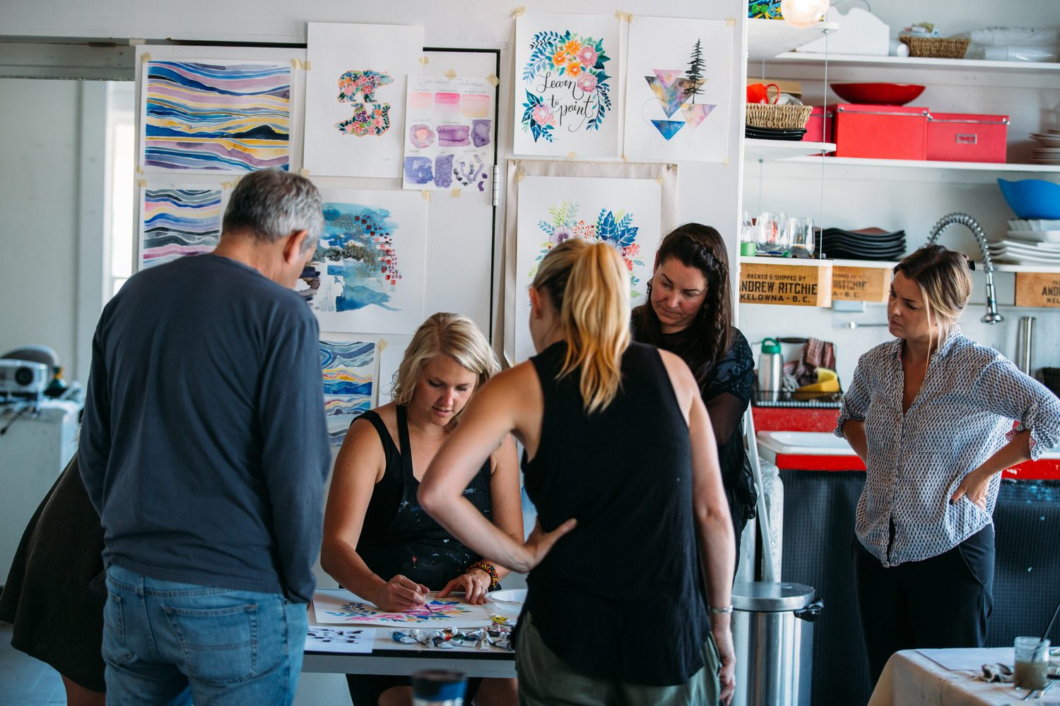 Workshop discussion in front of watercolour examples on the studio wall.