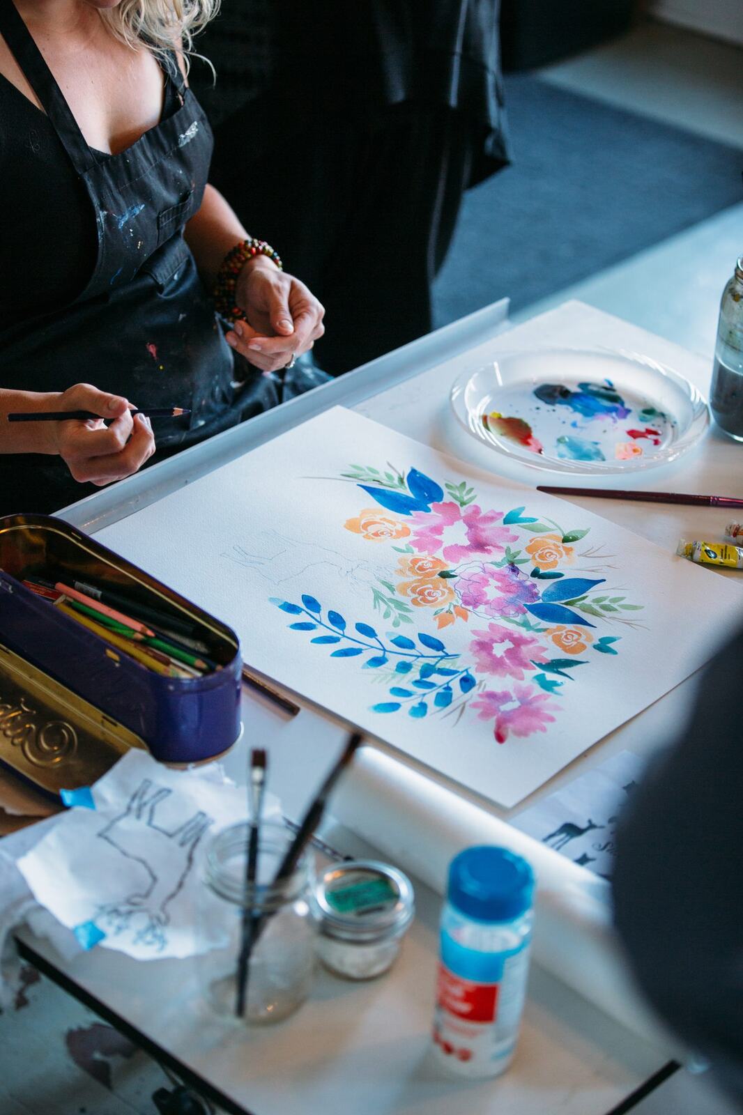 Workshop discussion in front of watercolour examples on the studio wall.