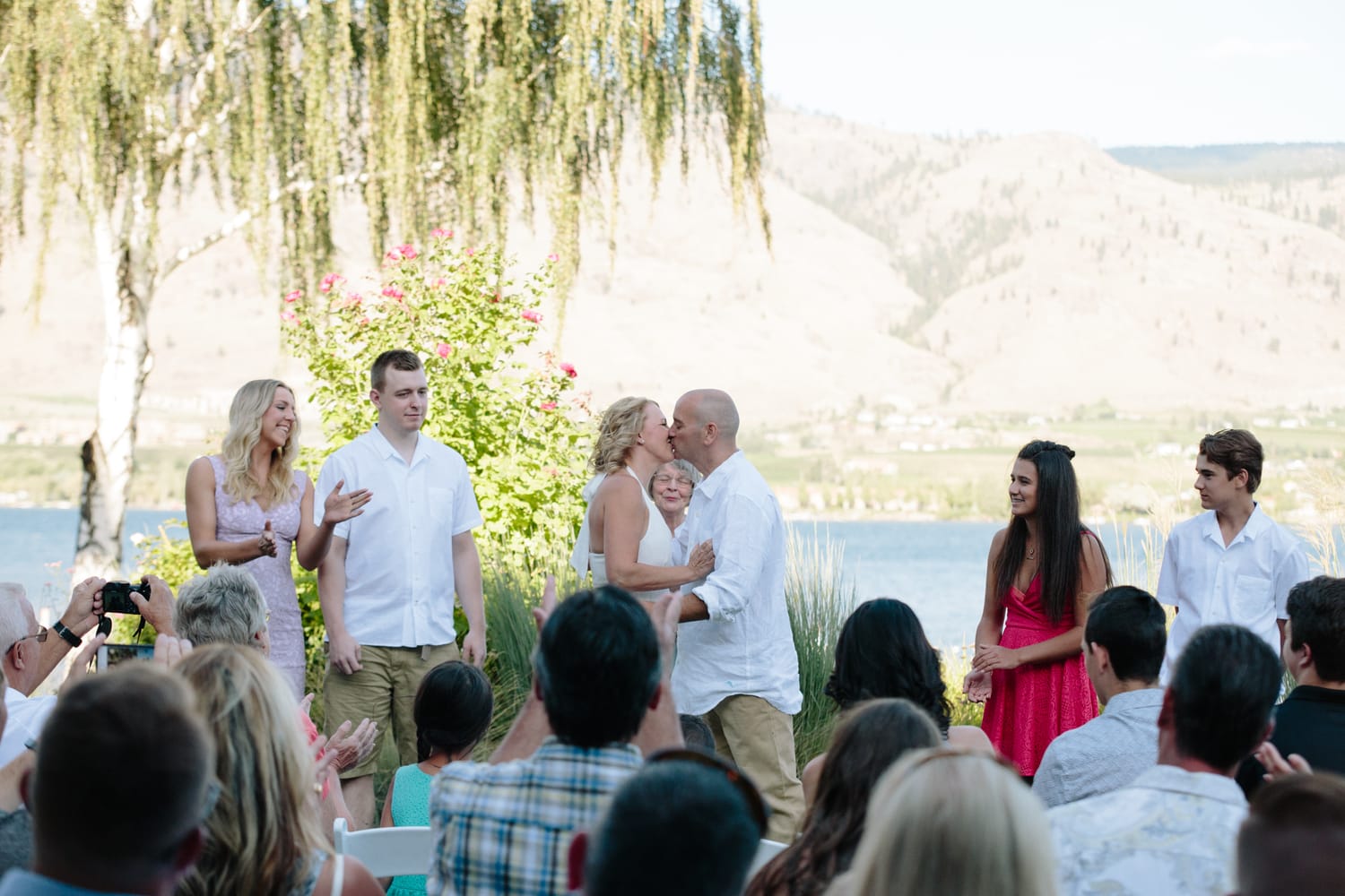 Leeanne and Kelly weddings story frame 19: A Watermark Beach Resort wedding in Osoyoos, built around lakefront context, grown-family connection and careful, big-hearted coverage..