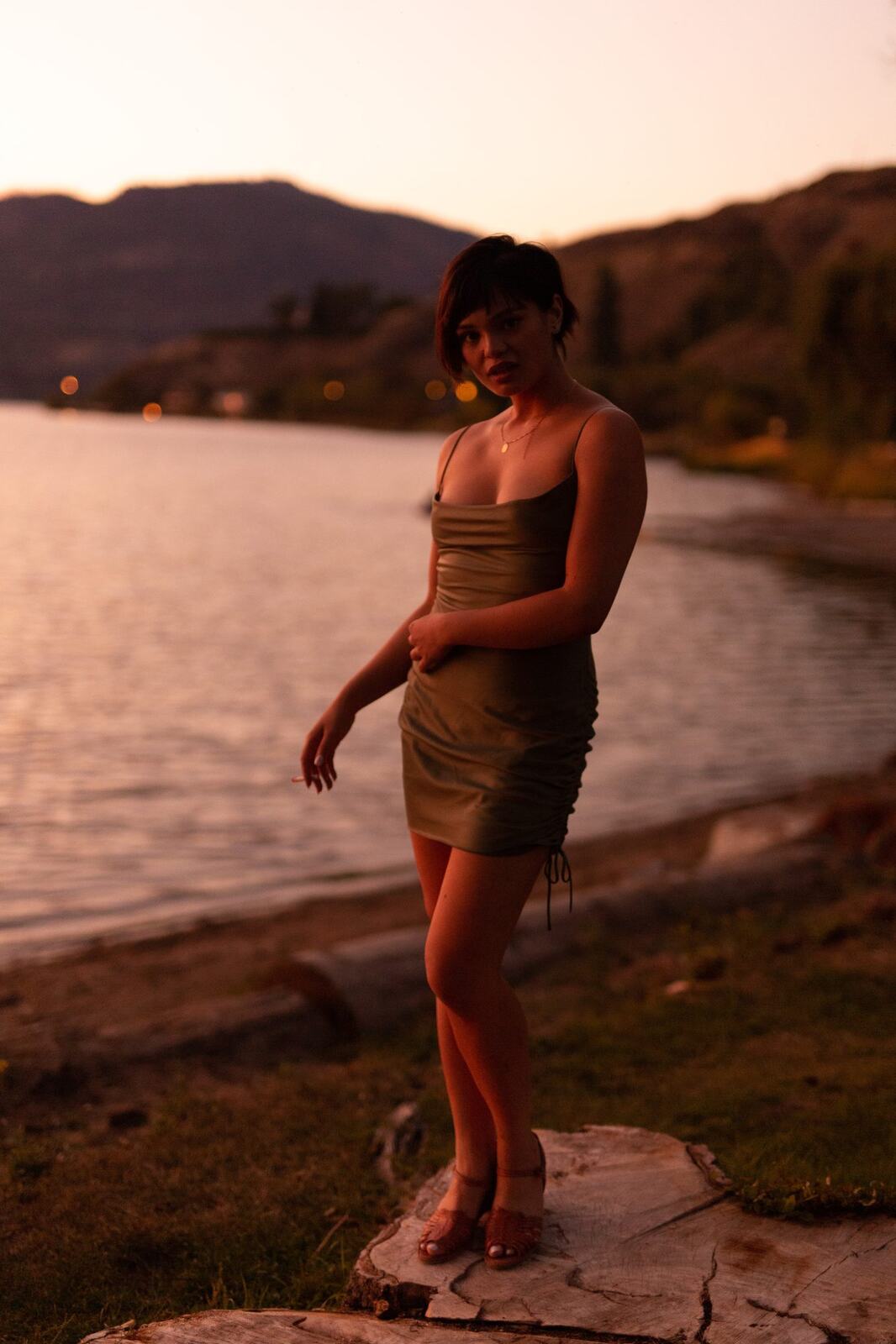 Lucy at the Water’s Edge portraits story frame 3: Lucy at the water’s edge as sunset slips into moonlight, moving from the shoreline and rocks to quiet close portraits and a warm-lit garden after dark. Photographed in Kelowna, BC.