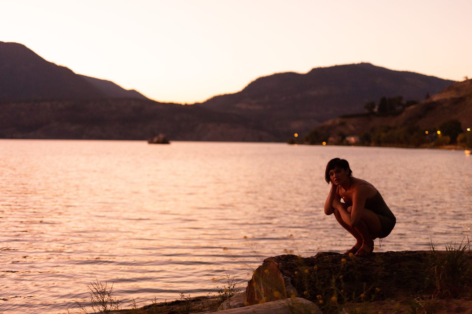 Lucy at the Water’s Edge portraits story frame 4: Lucy at the water’s edge as sunset slips into moonlight, moving from the shoreline and rocks to quiet close portraits and a warm-lit garden after dark. Photographed in Kelowna, BC.