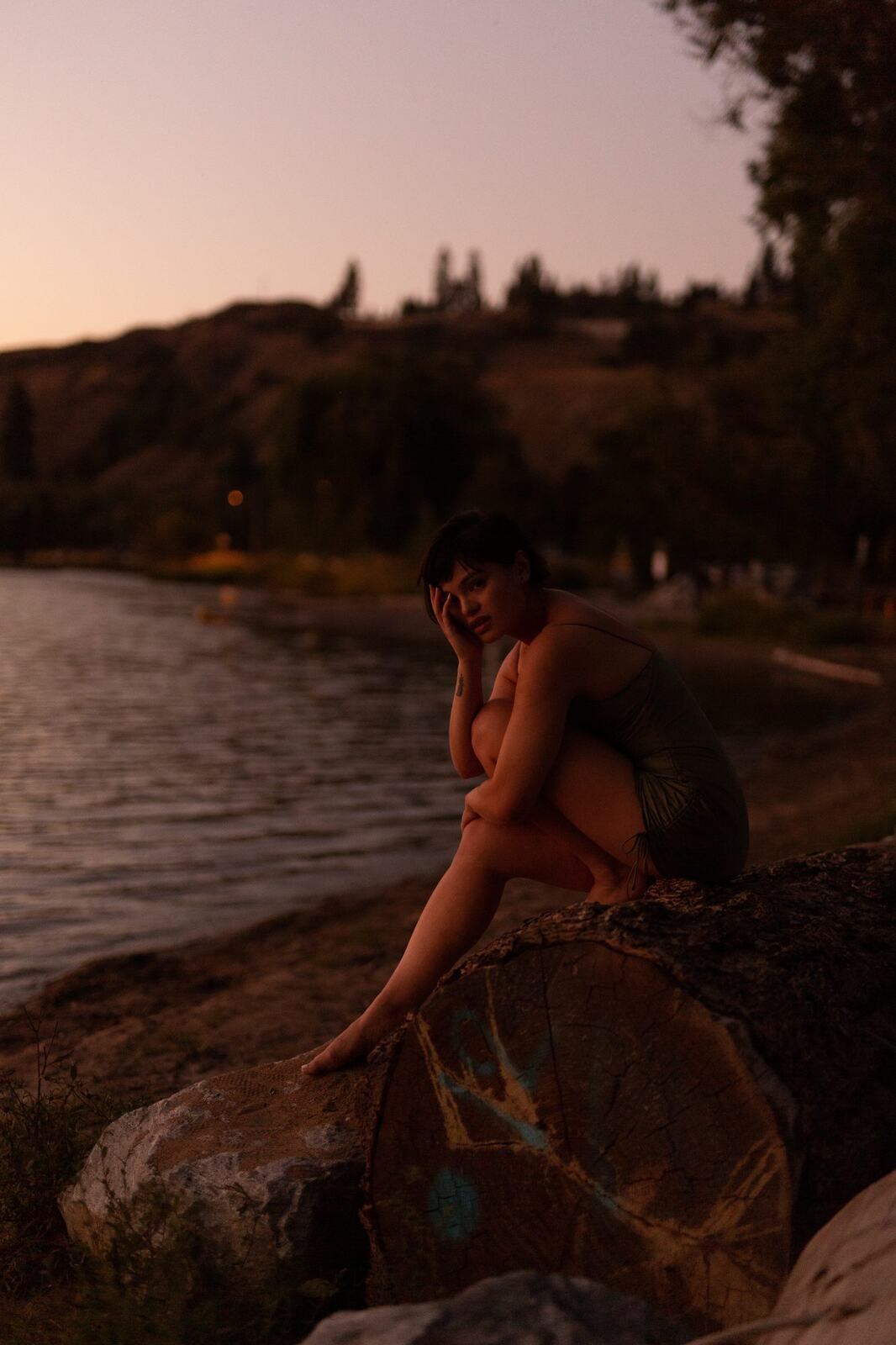 Lucy at the Water’s Edge portraits story frame 7: Lucy at the water’s edge as sunset slips into moonlight, moving from the shoreline and rocks to quiet close portraits and a warm-lit garden after dark. Photographed in Kelowna, BC.