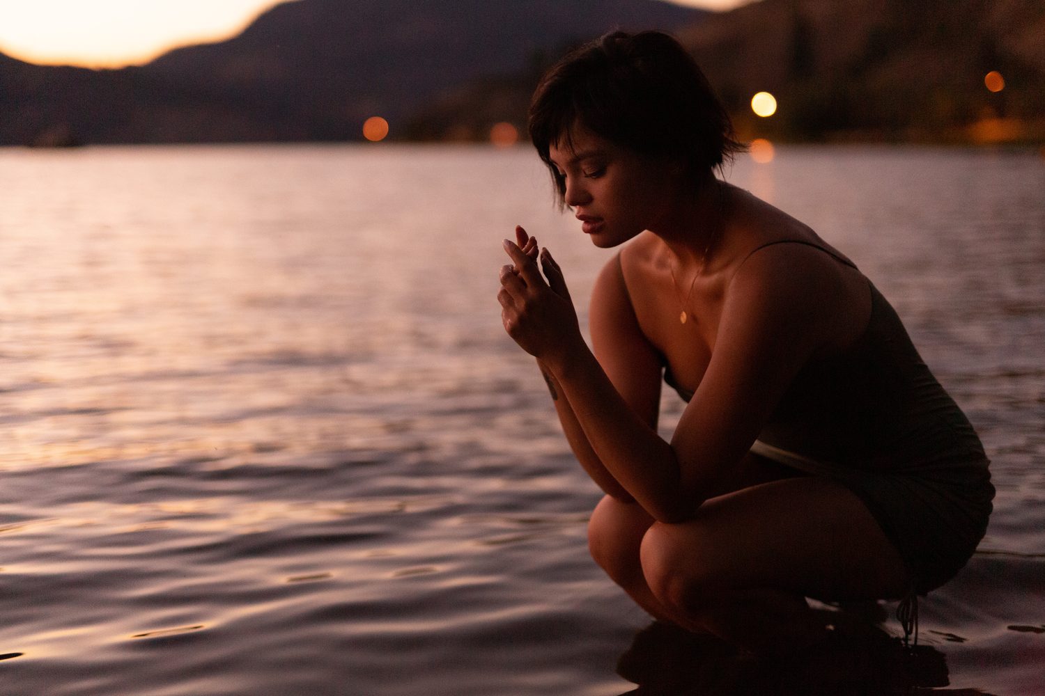 Lucy at the Water’s Edge portraits story frame 13: Lucy at the water’s edge as sunset slips into moonlight, moving from the shoreline and rocks to quiet close portraits and a warm-lit garden after dark. Photographed in Kelowna, BC.