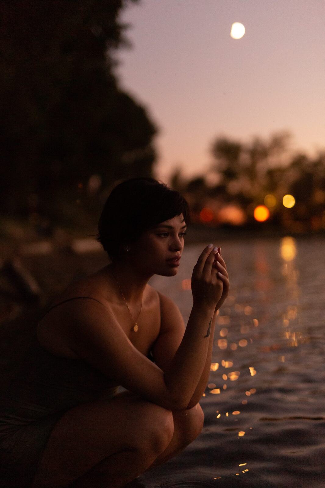 Lucy at the Water’s Edge portraits story frame 15: Lucy at the water’s edge as sunset slips into moonlight, moving from the shoreline and rocks to quiet close portraits and a warm-lit garden after dark. Photographed in Kelowna, BC.