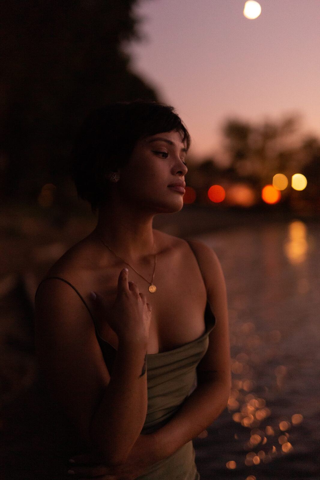 Lucy at the Water’s Edge portraits story frame 18: Lucy at the water’s edge as sunset slips into moonlight, moving from the shoreline and rocks to quiet close portraits and a warm-lit garden after dark. Photographed in Kelowna, BC.