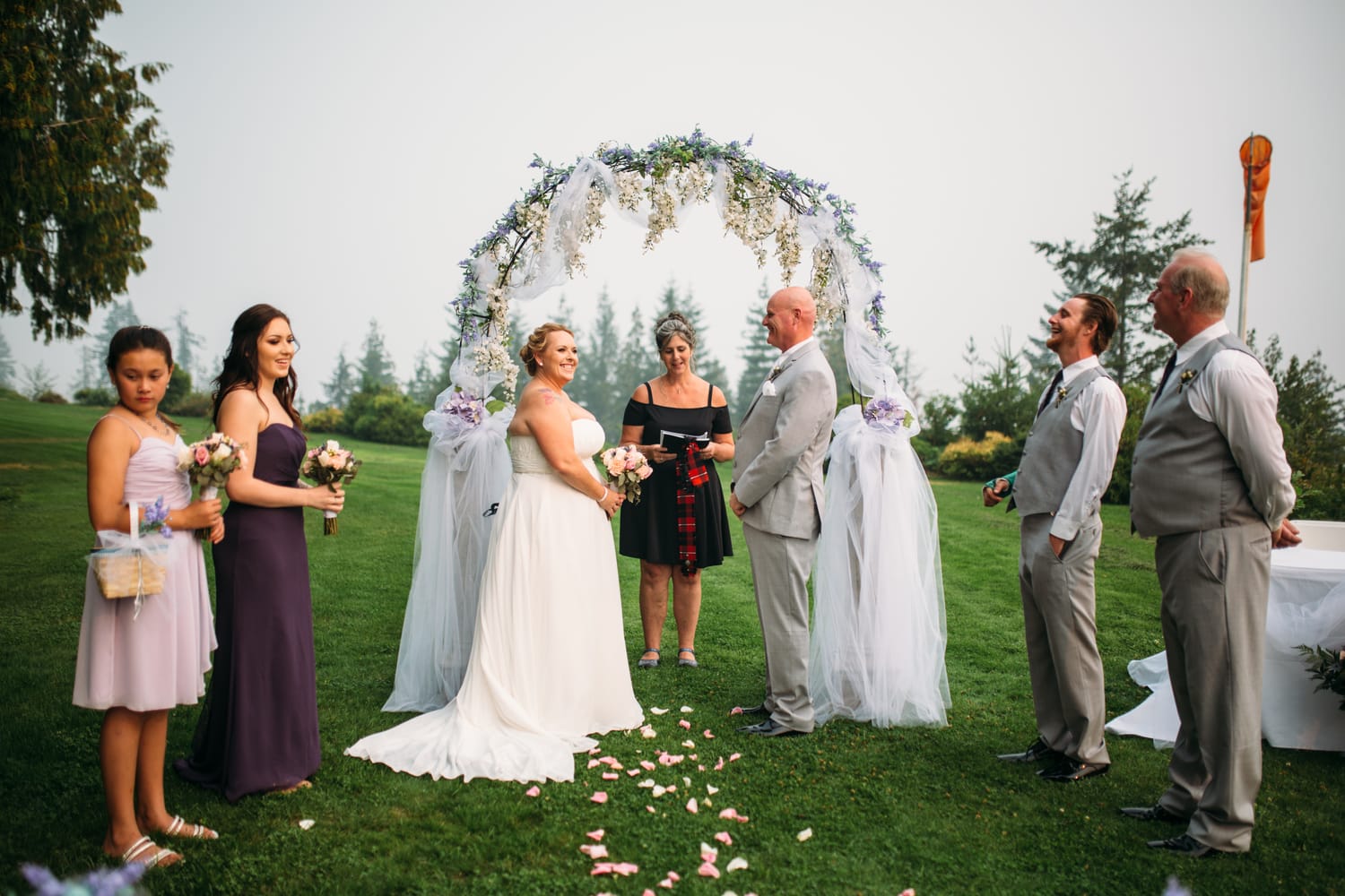 Marie and Mark weddings story frame 15: A Mabel Lake Airpark wedding in the North Okanagan, with grass-runway scenery, open-air photos and sweet family help around makeup, flowers and petals..