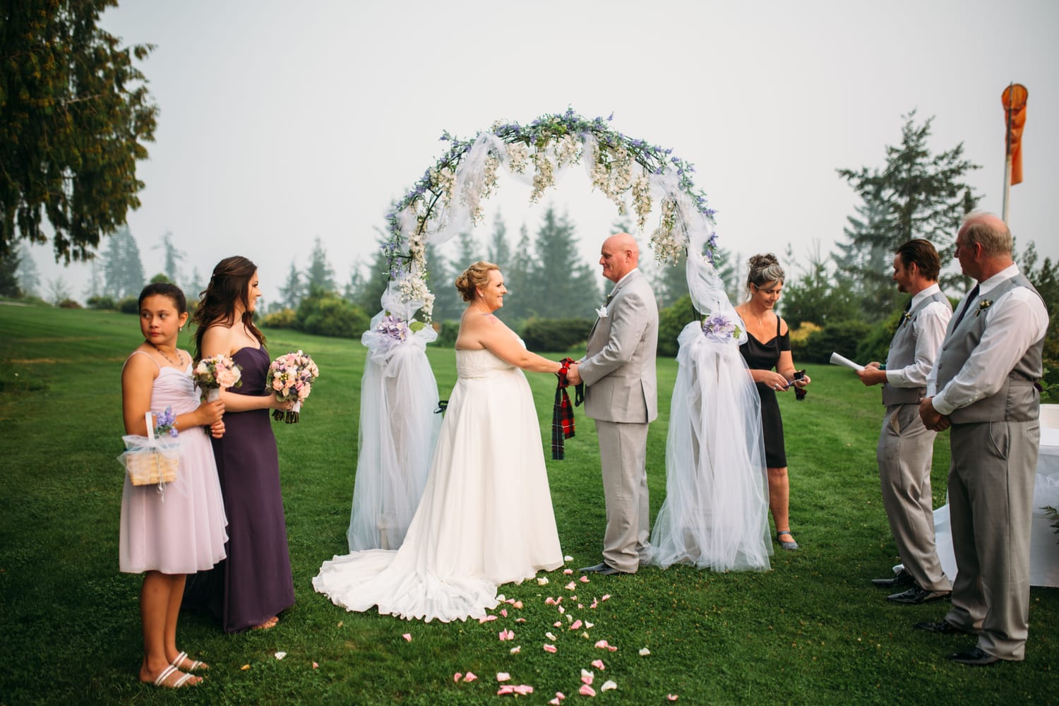 Marie and Mark weddings story frame 17: A Mabel Lake Airpark wedding in the North Okanagan, with grass-runway scenery, open-air photos and sweet family help around makeup, flowers and petals..