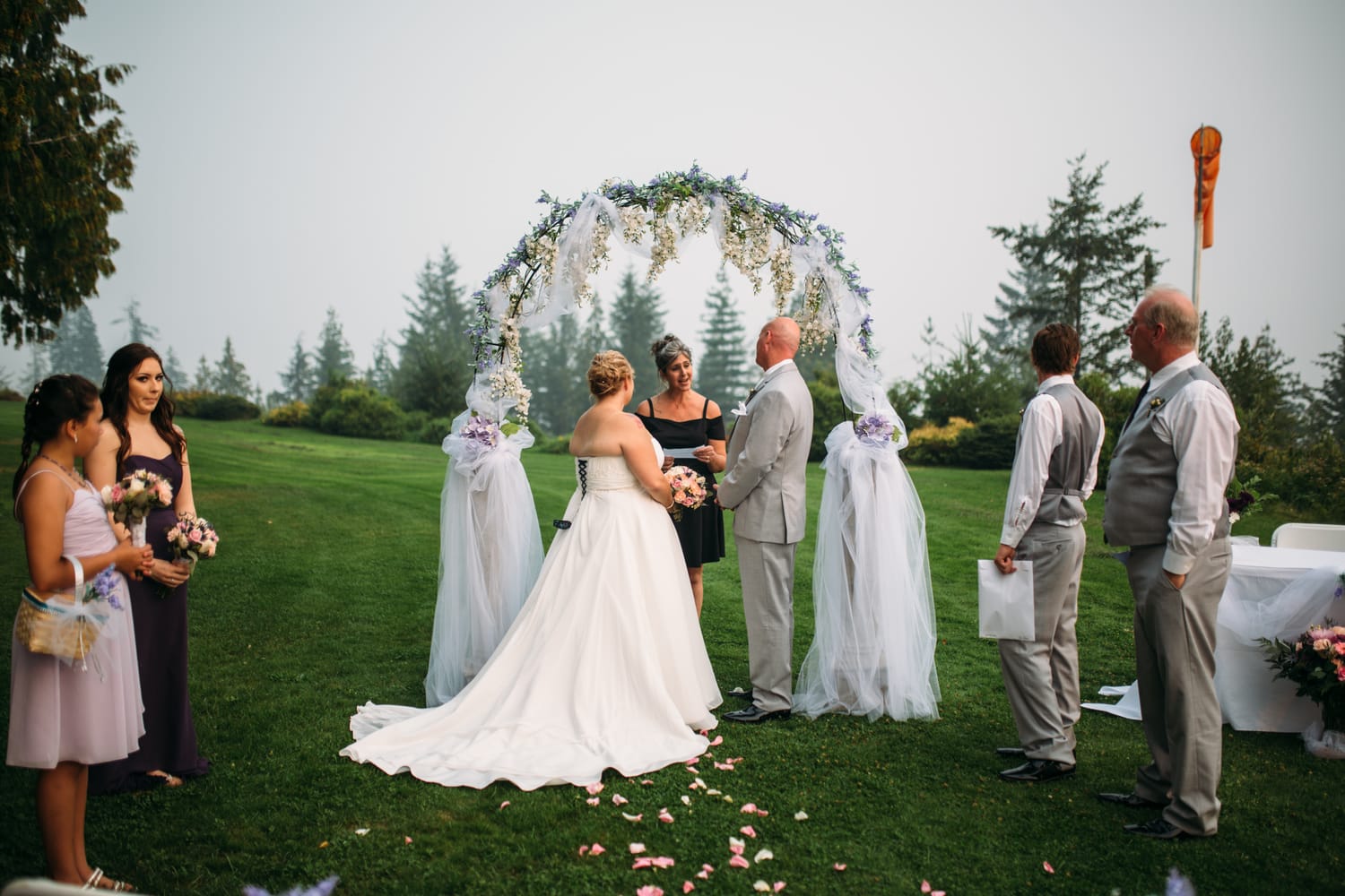 Marie and Mark weddings story frame 20: A Mabel Lake Airpark wedding in the North Okanagan, with grass-runway scenery, open-air photos and sweet family help around makeup, flowers and petals..