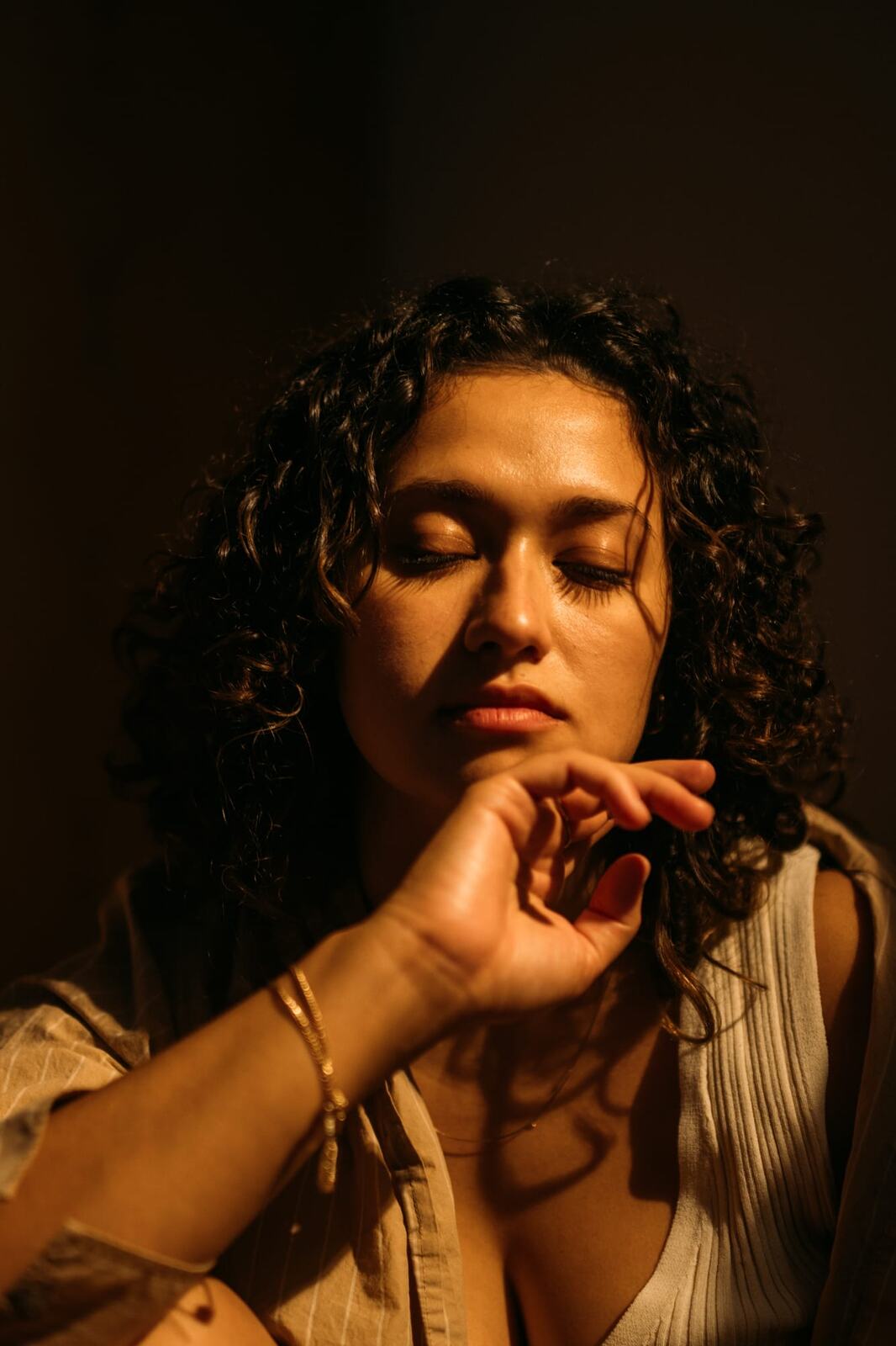 Marina in Warm Window Light portraits story frame 8: Marina in warm indoor light, with amber shadow, denim, black robe, green styling and an intimate editorial portrait mood.