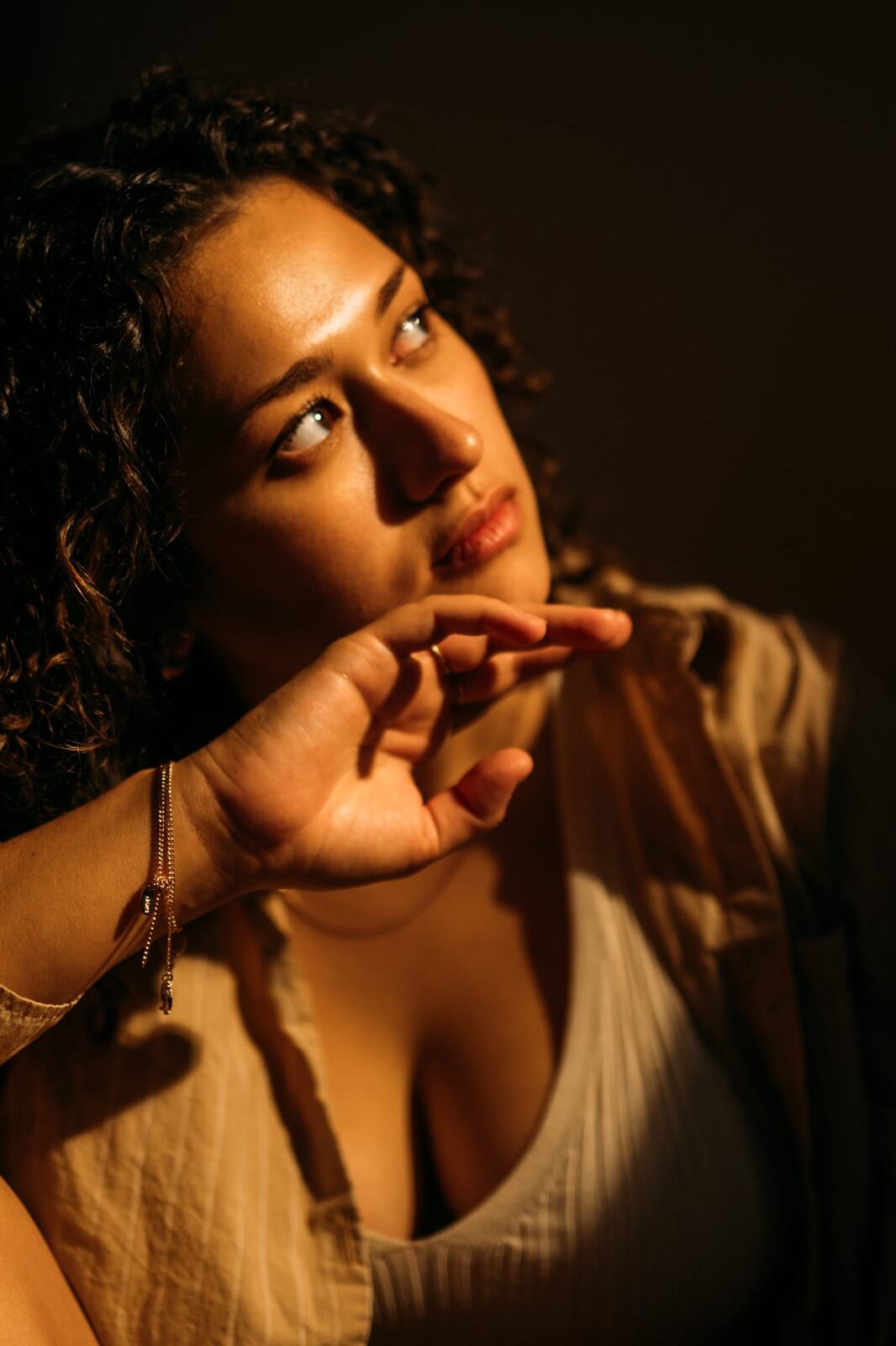 Marina in Warm Window Light portraits story frame 6: Marina in warm indoor light, with amber shadow, denim, black robe, green styling and an intimate editorial portrait mood.