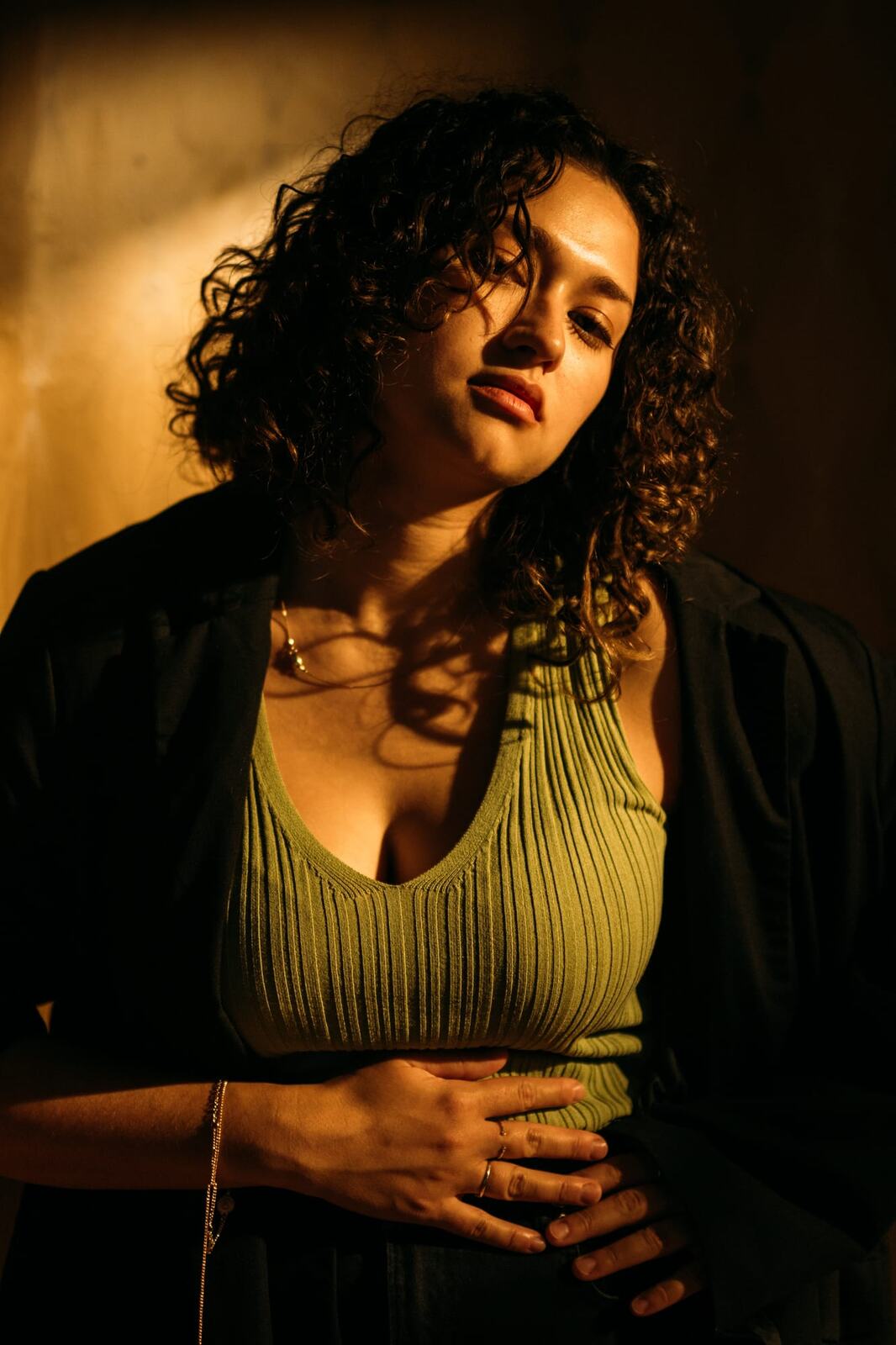 Marina in Warm Window Light portraits story frame 14: Marina in warm indoor light, with amber shadow, denim, black robe, green styling and an intimate editorial portrait mood.