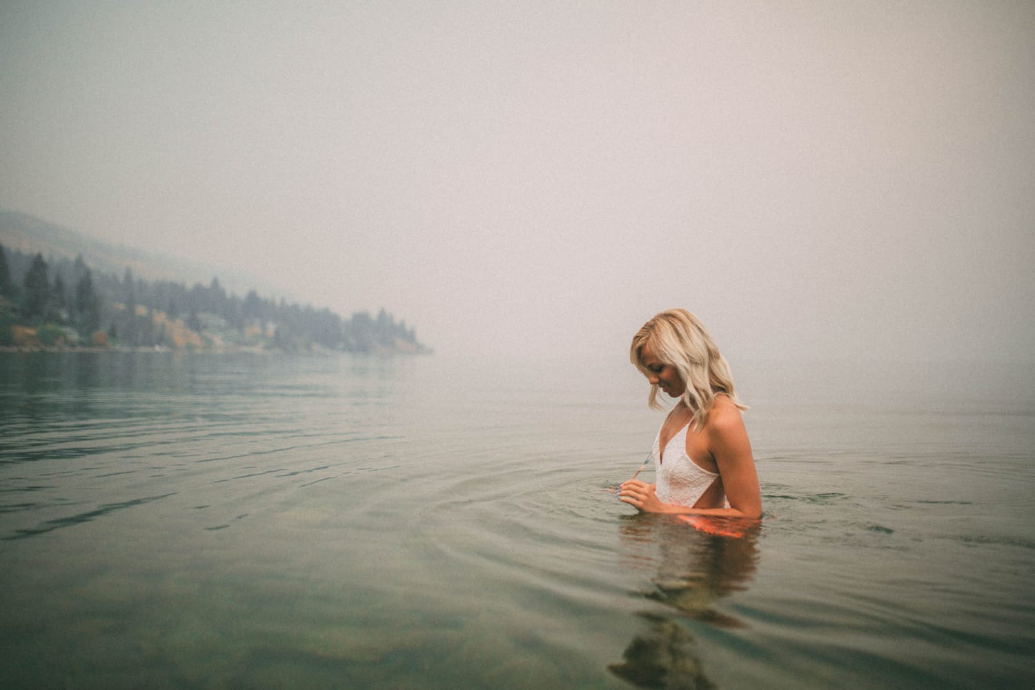 Megan Shallow portraits story frame 3: A fog-soft Kelowna lake portrait session for Megan Shallow, with water, orange dress movement, close body-language frames and quiet birds cutting through the mist.