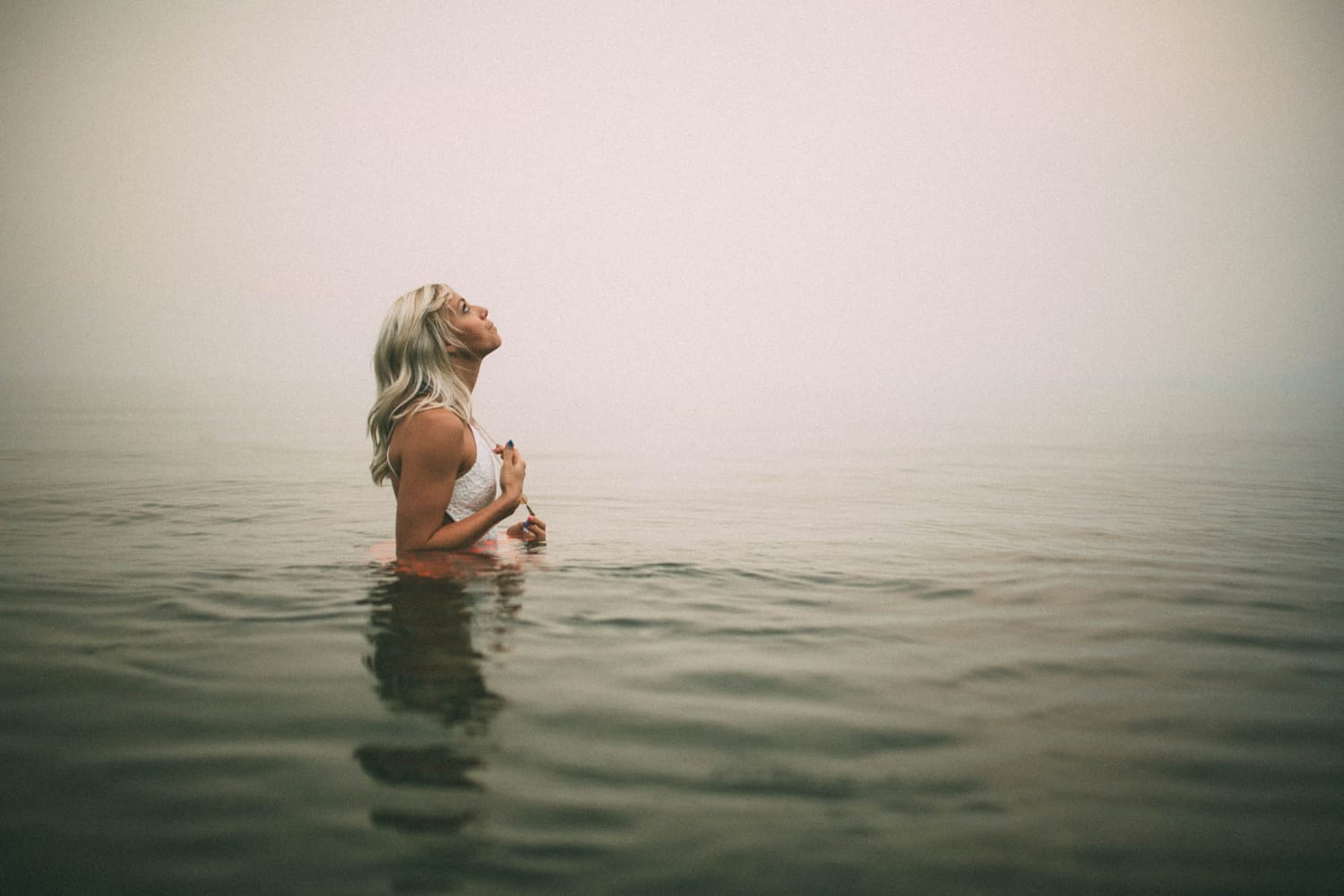 Megan Shallow portraits story frame 9: A fog-soft Kelowna lake portrait session for Megan Shallow, with water, orange dress movement, close body-language frames and quiet birds cutting through the mist.