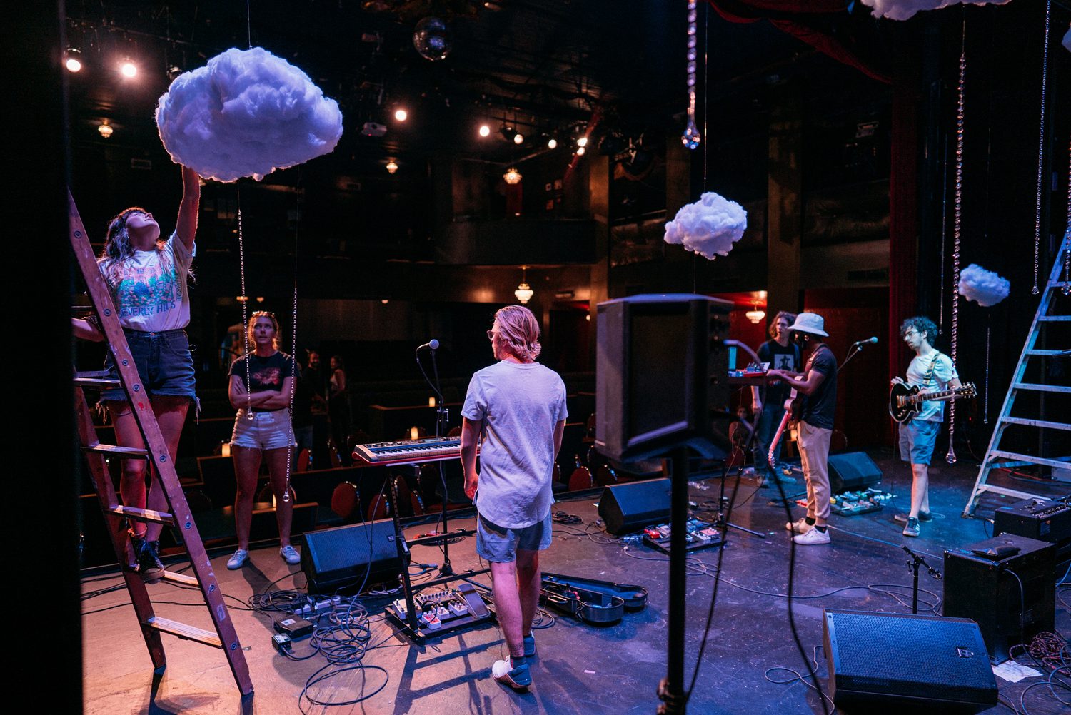 Wide blue-lit stage with a solo vocalist and instruments set at Kelowna Actors Studio.