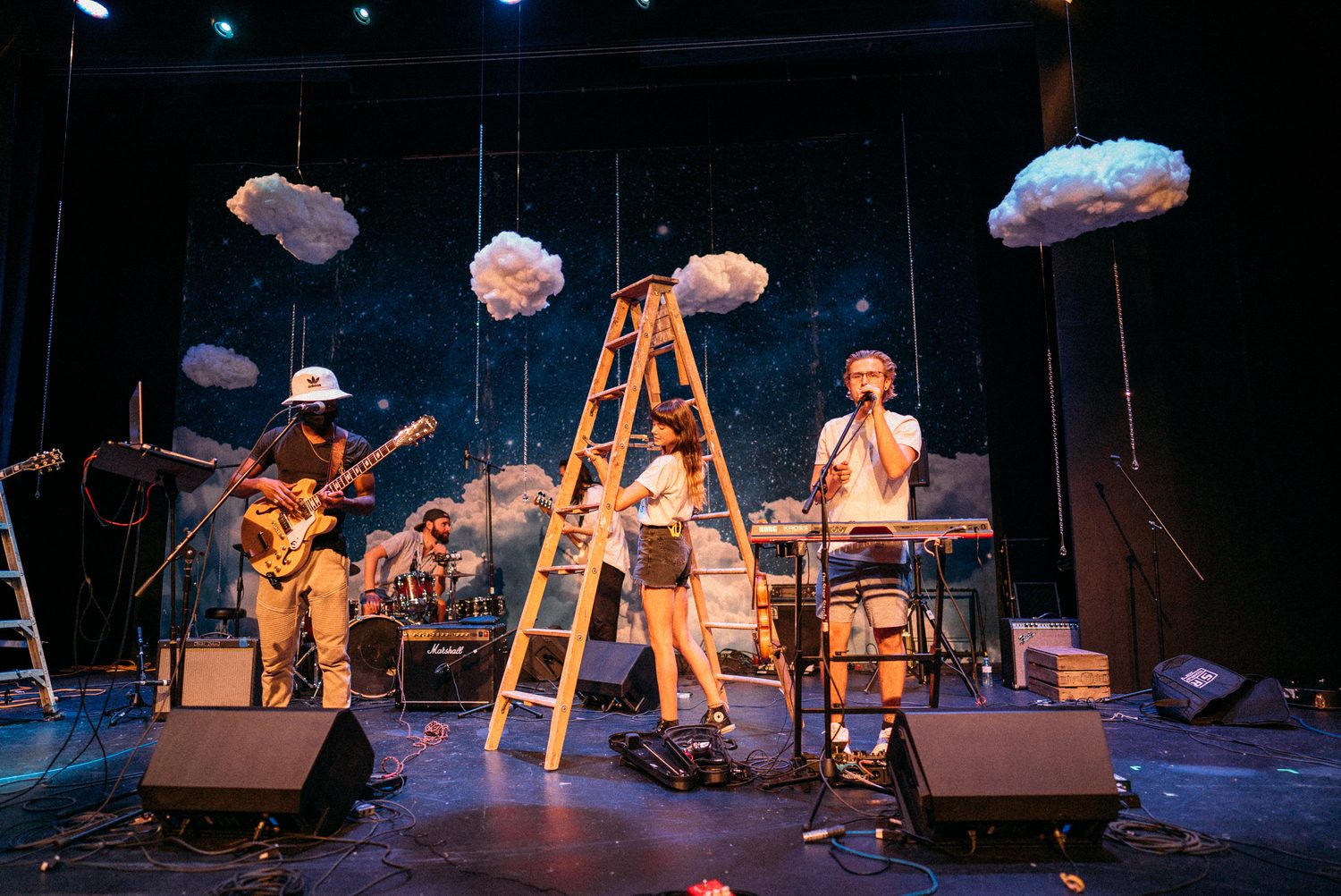 Wider theatre view with MusicBC performers and blue stage lighting.