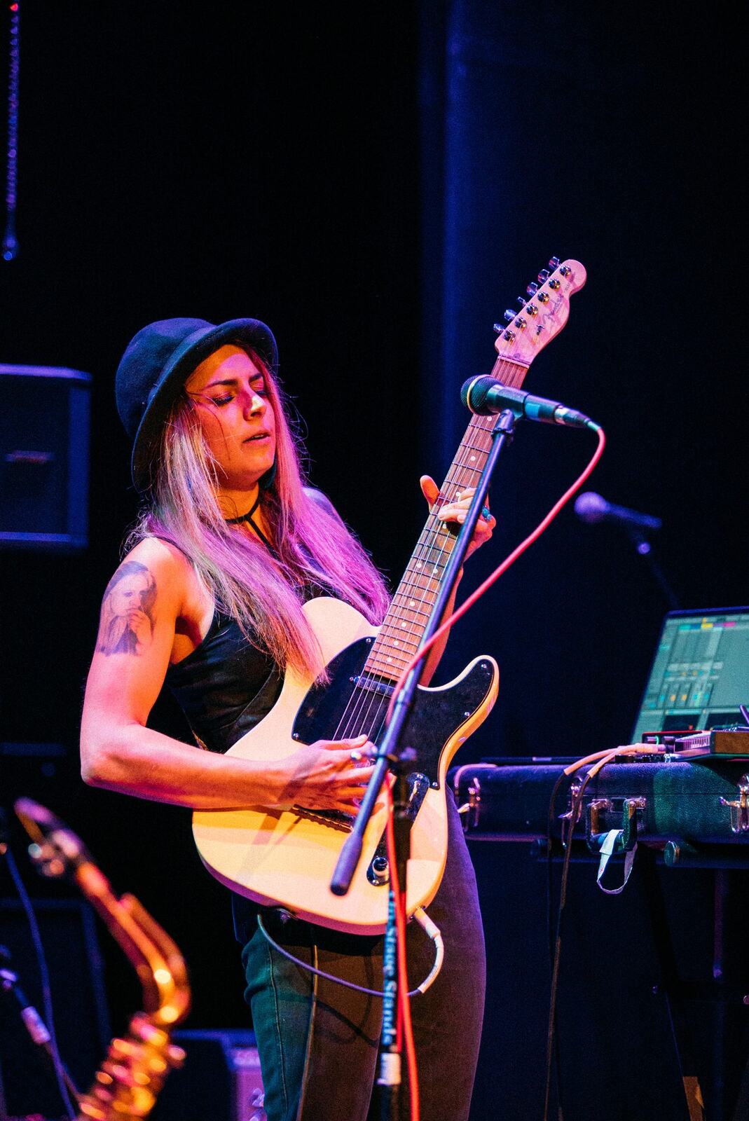 Guitarist singing in a white outfit under warm blue stage light.