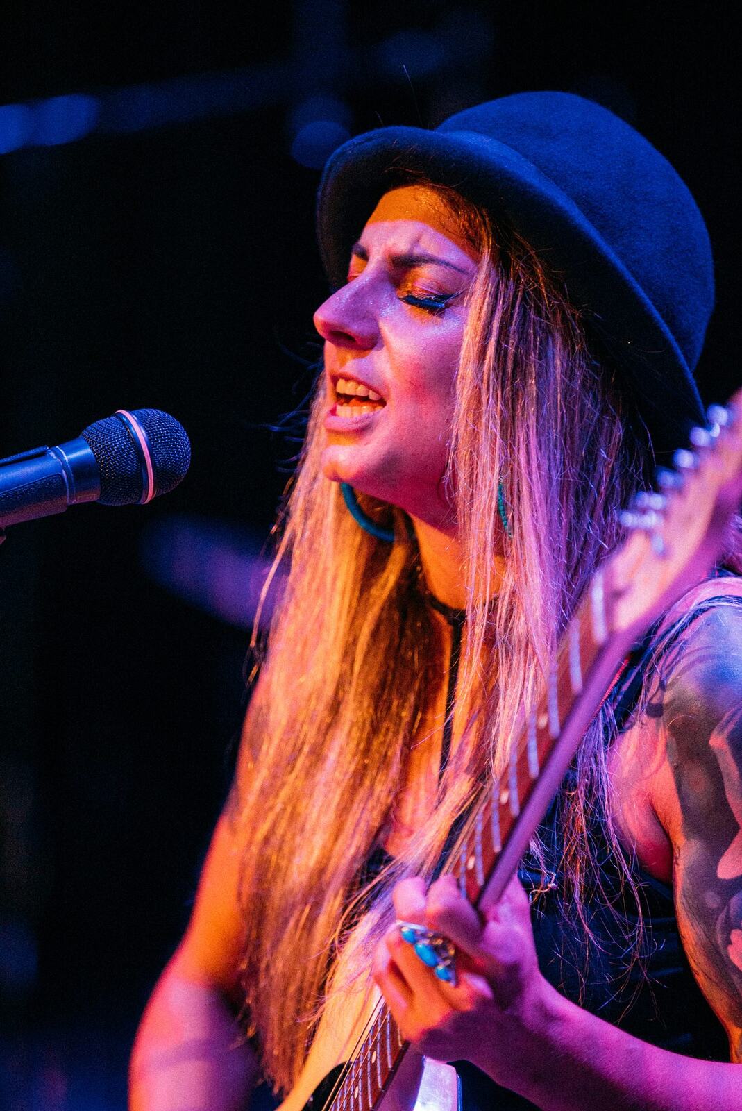 Full-length singer-guitarist at microphone against a dark stage.