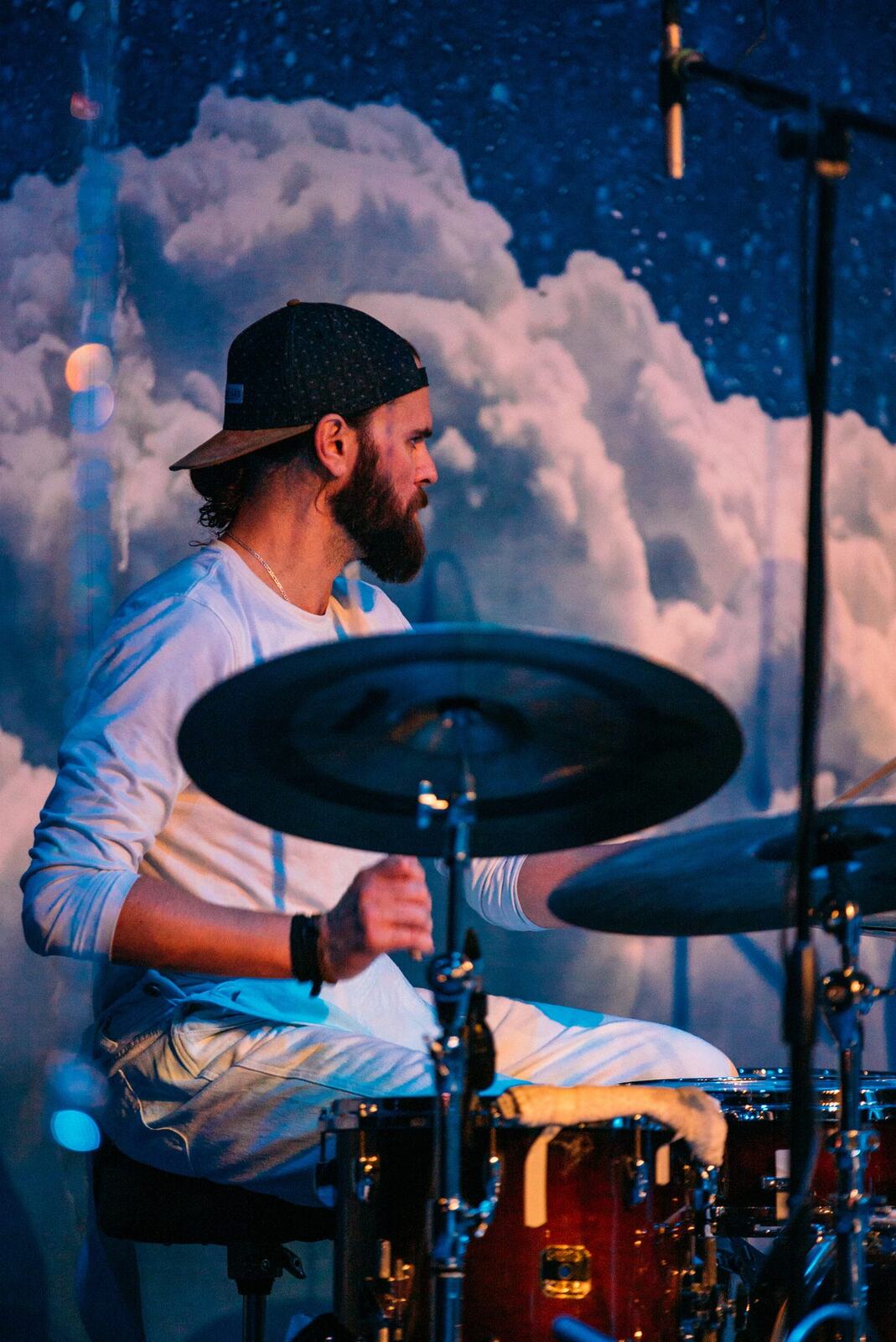 Bassist singing at microphone with drummer behind.