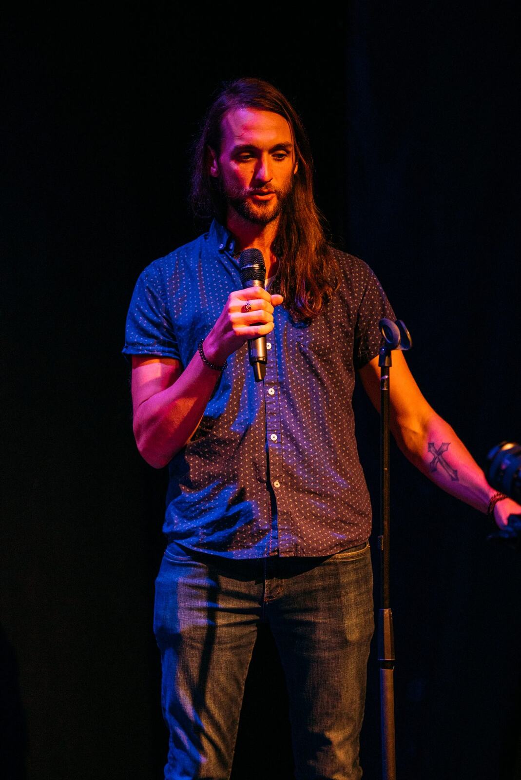 Wide blue-lit stage with a solo vocalist and instruments set at Kelowna Actors Studio.